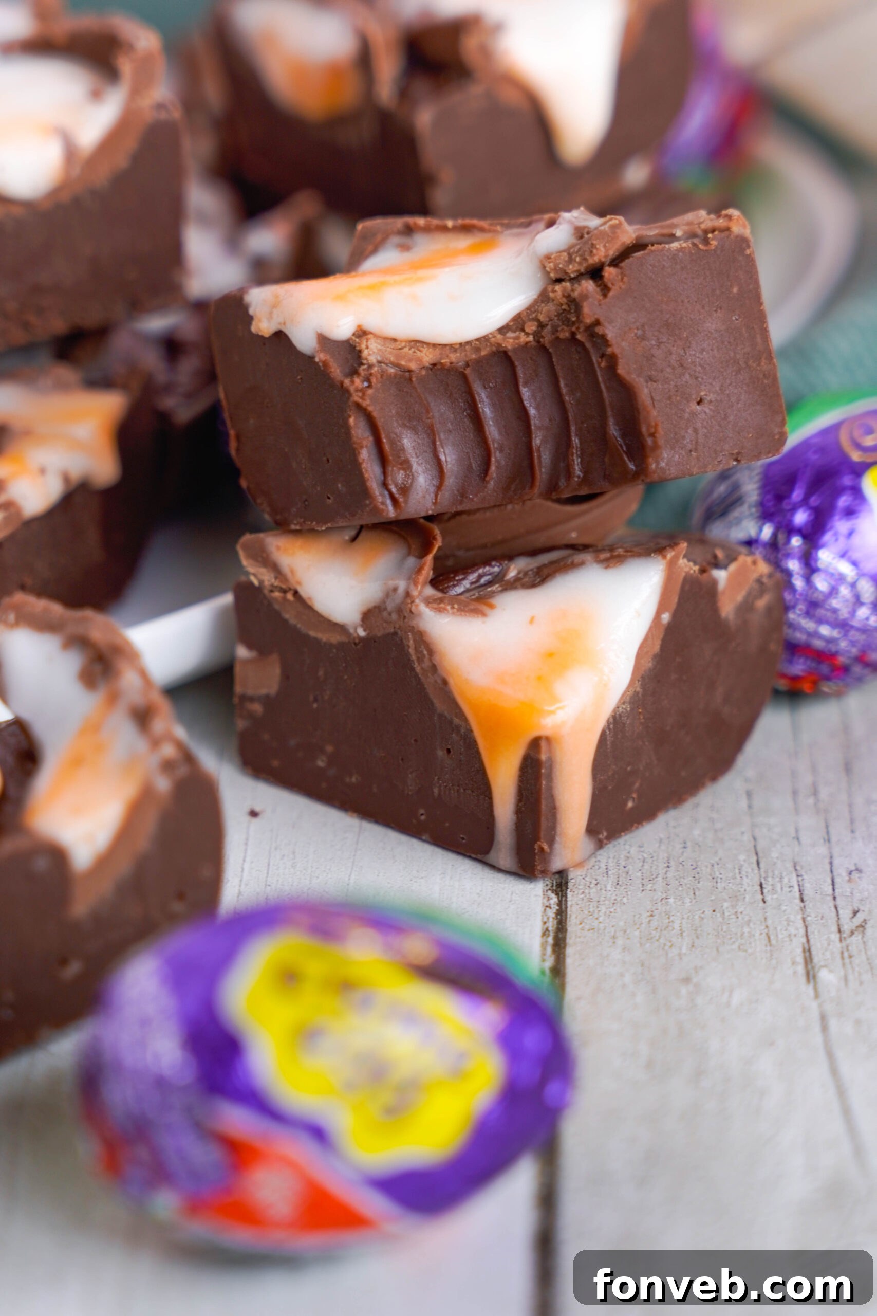 Front view of two pieces of Cadbury Cream Fudge stacked with a bite removed from the top piece.