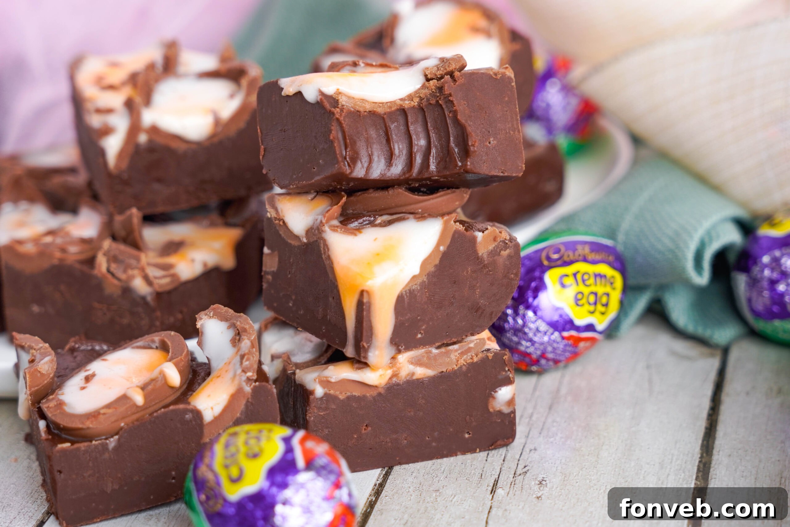 Front view of two pieces of Cadbury Cream Fudge stacked with a bite removed from the top piece.