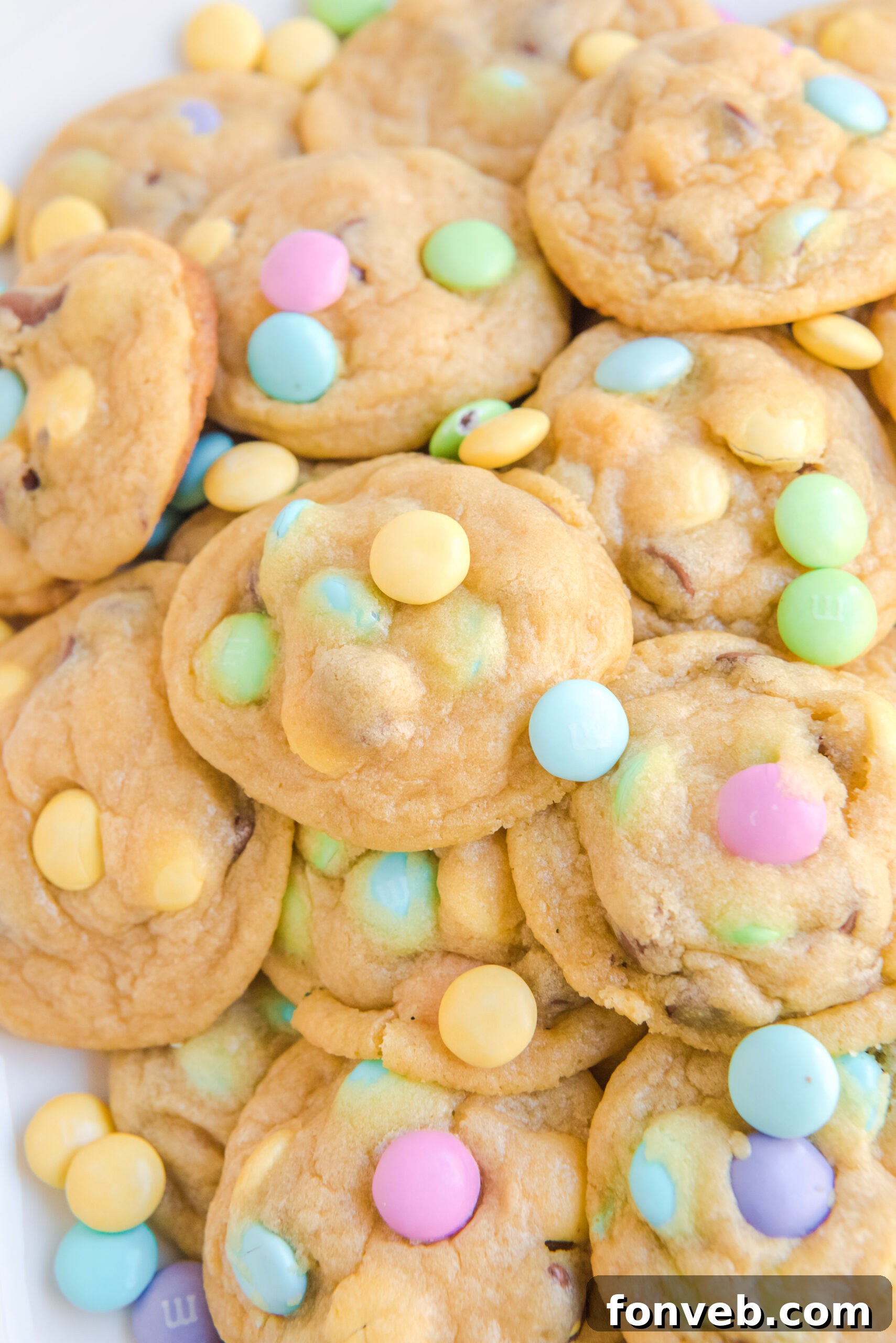 Close up view of a stack of pastel-colored Easter Pudding Cookies, showcasing their soft texture and colorful M&Ms.