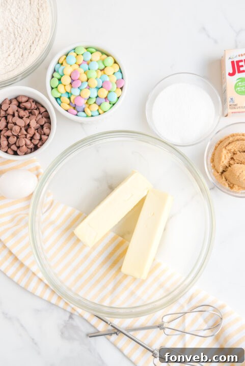 A close-up of cookie dough mixed with chocolate chips and pastel M&Ms.