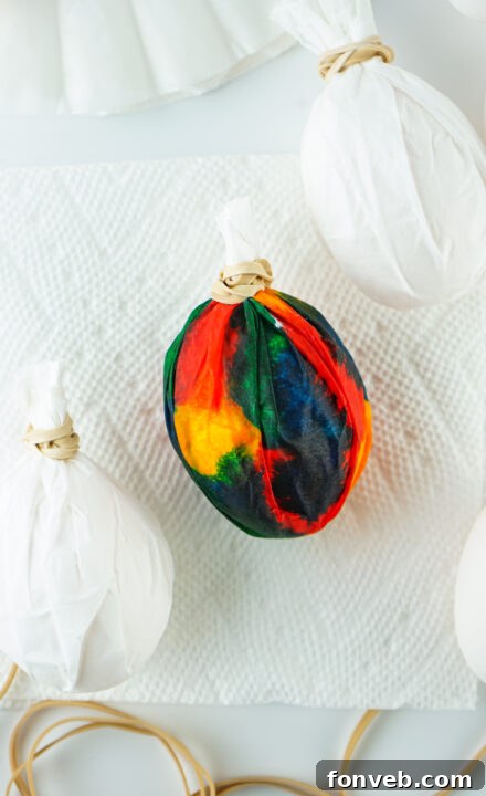 A coffee filter wrapped egg fully covered in various food coloring drops.