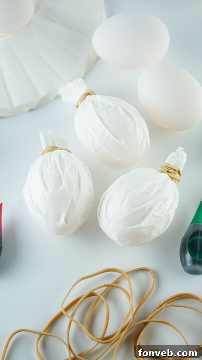 Applying drops of food coloring to a coffee filter wrapped egg.