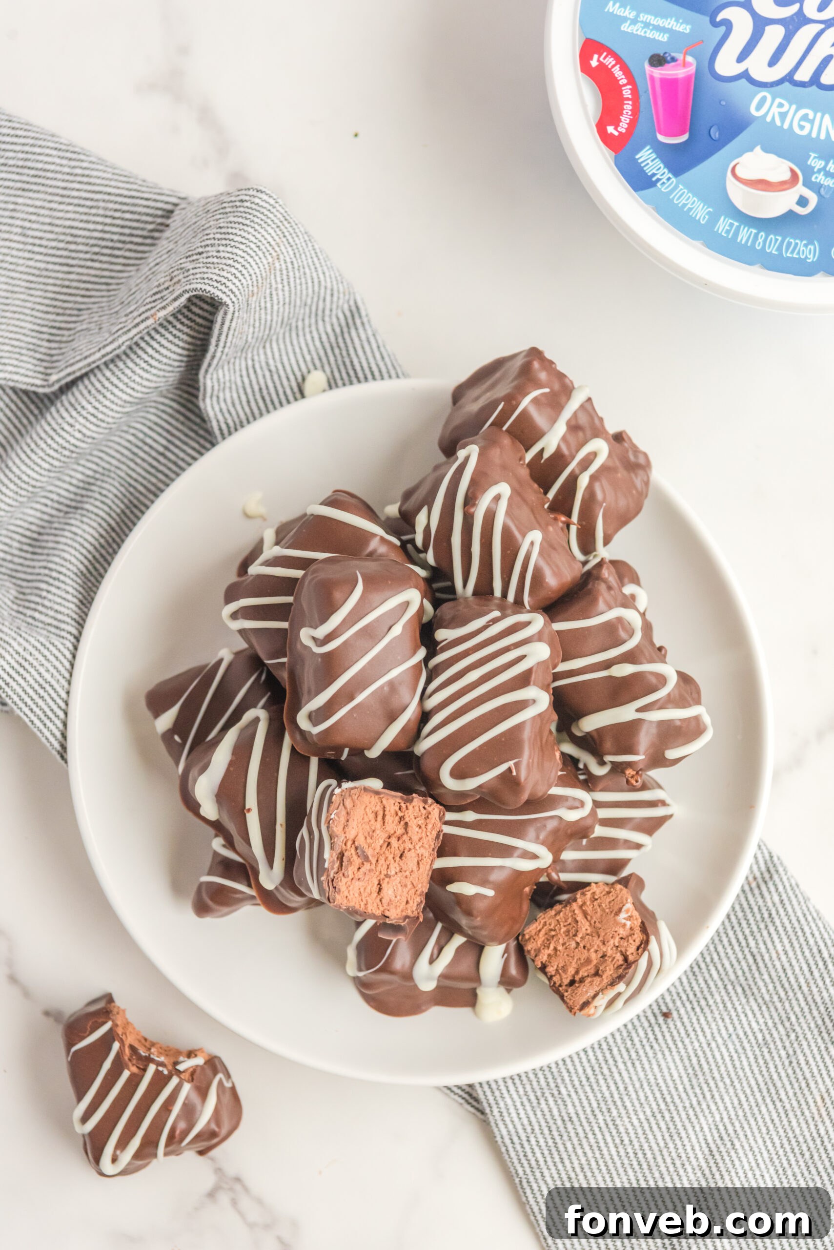 Sweet Cloud Candies 18 An overhead view of two halves of Cool Whip Candy bars, meticulously placed on top of a stack of full candy bars, highlighting their layered texture.