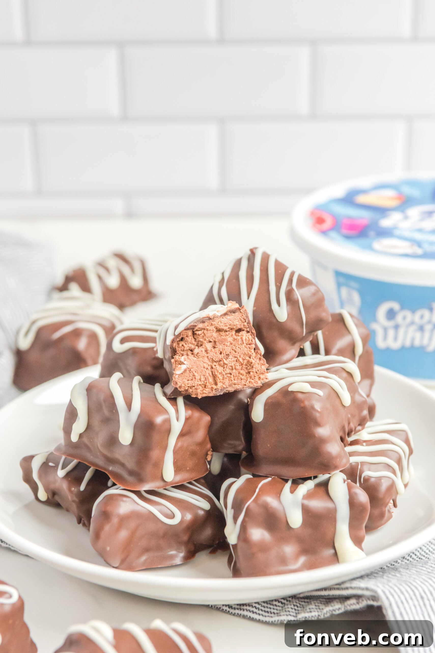 Sweet Cloud Candies 3 Front view of a perfectly arranged stack of Cool Whip Candy on a pristine white plate, showcasing its appealing texture and chocolate coating.