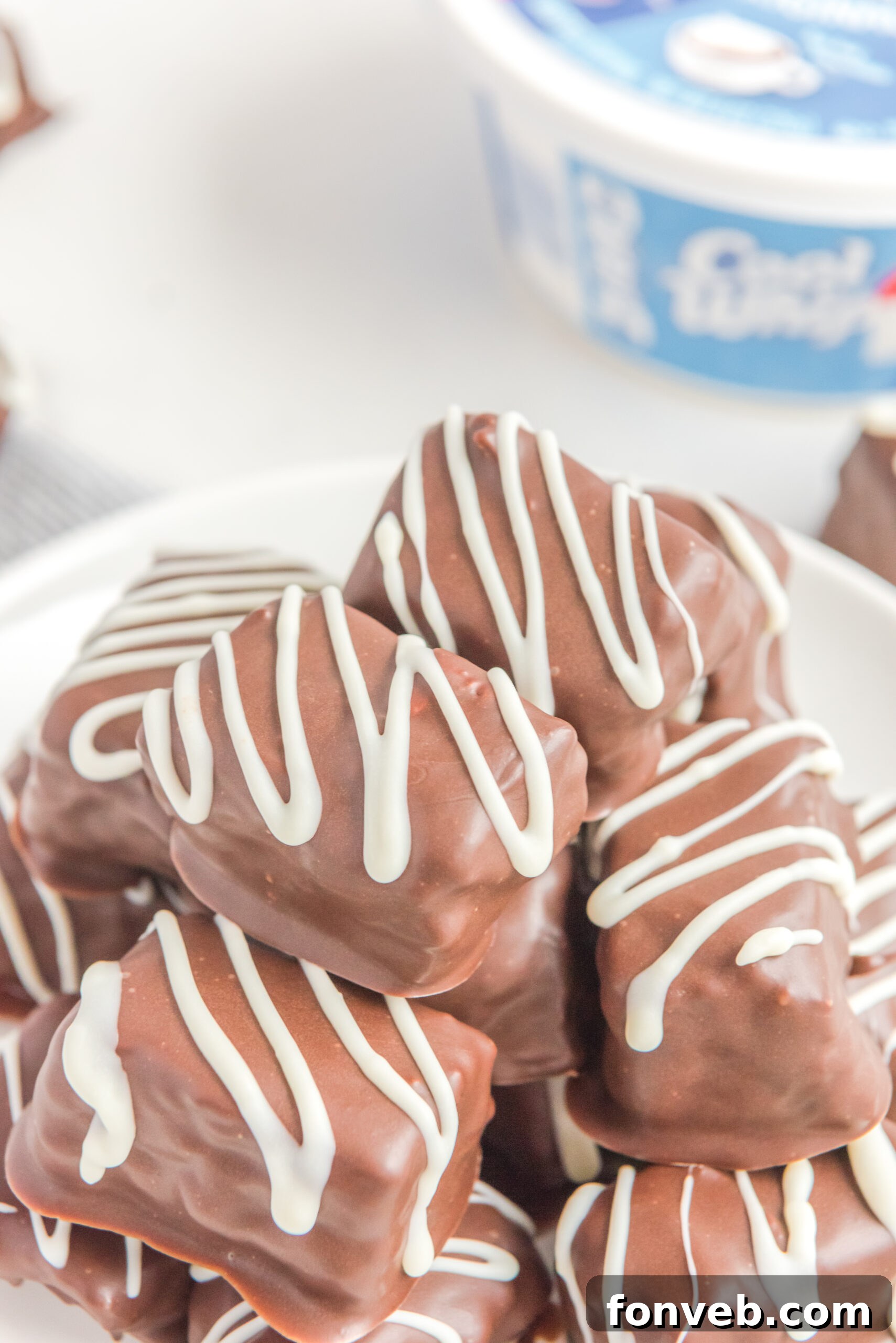 Sweet Cloud Candies 5 An overhead shot showcasing a stack of Cool Whip Candy on a white plate, highlighting its uniform appearance and appealing coating.