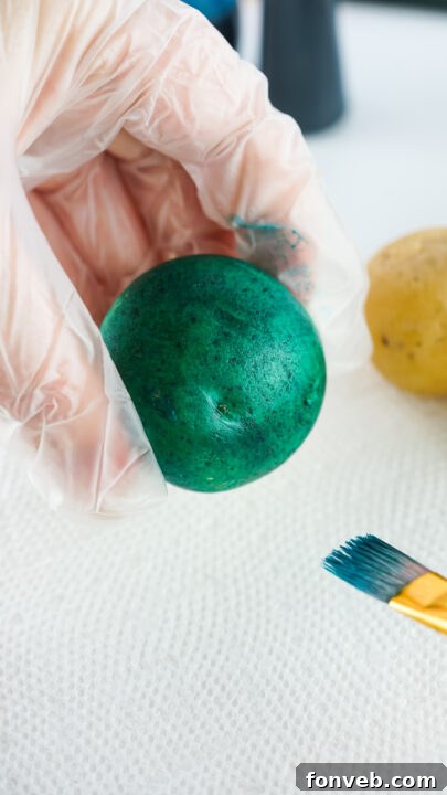 Step-by-step image showing a fully dyed Easter egg potato drying on paper towels.
