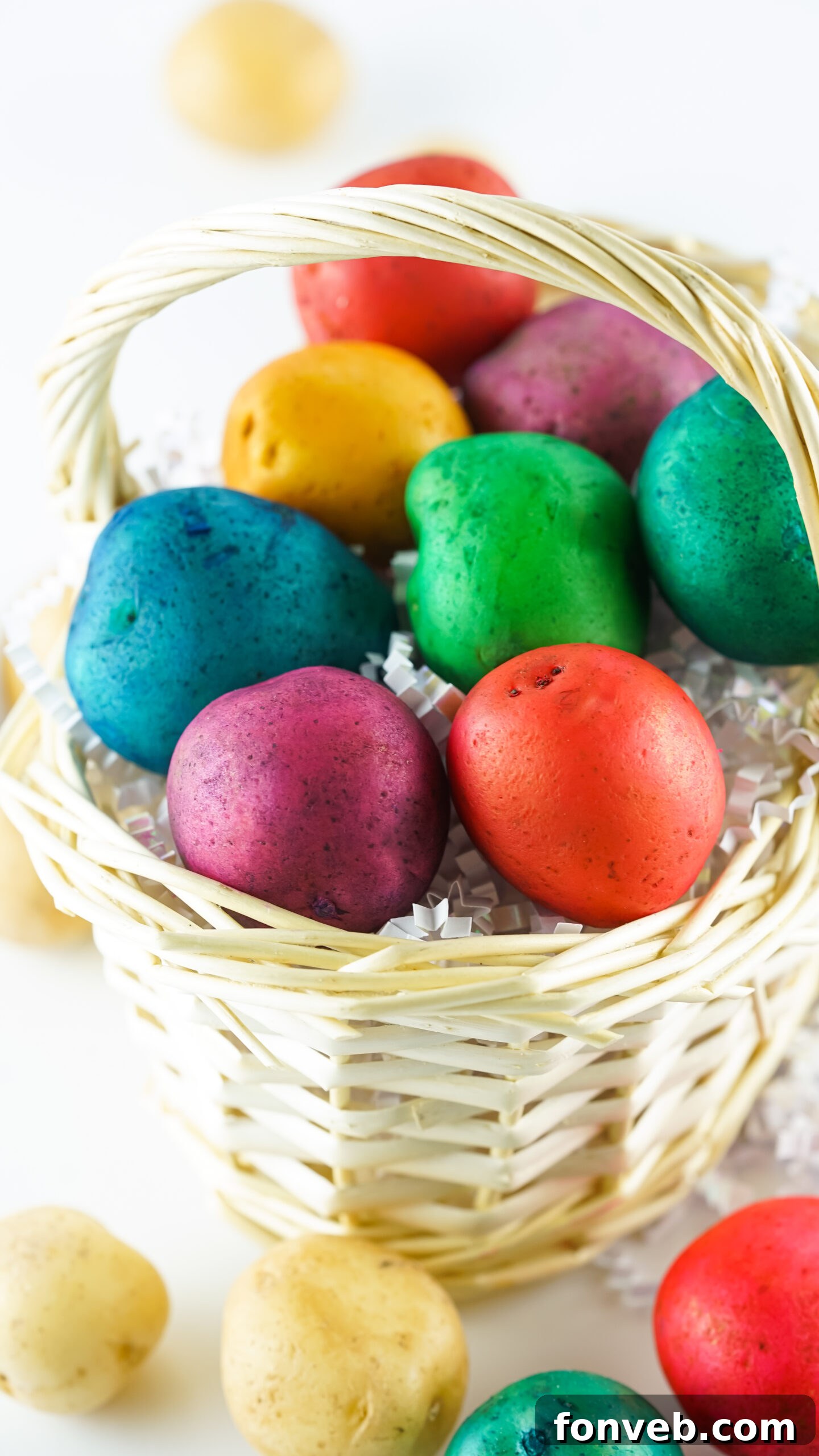Front view of the Dyed Easter Egg Potatoes creatively arranged in a tan basket with a few green accents.