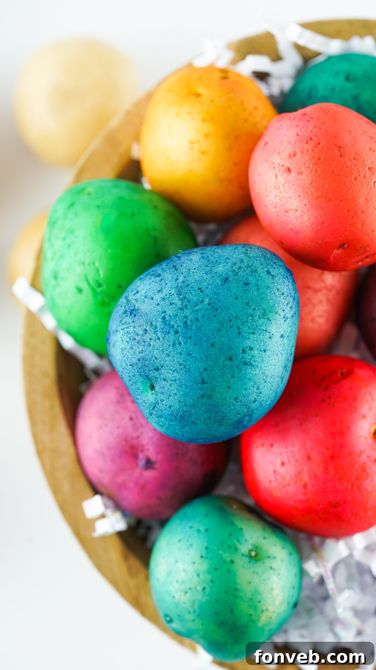 Overhead view of a beautiful collection of Dyed Easter Egg Potatoes presented in a simple brown bowl.