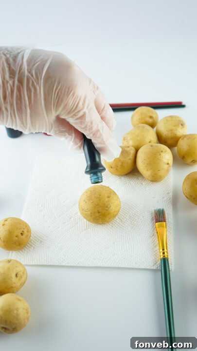 Step-by-step image of a hand applying dye to a potato with a paintbrush for the Easter craft.