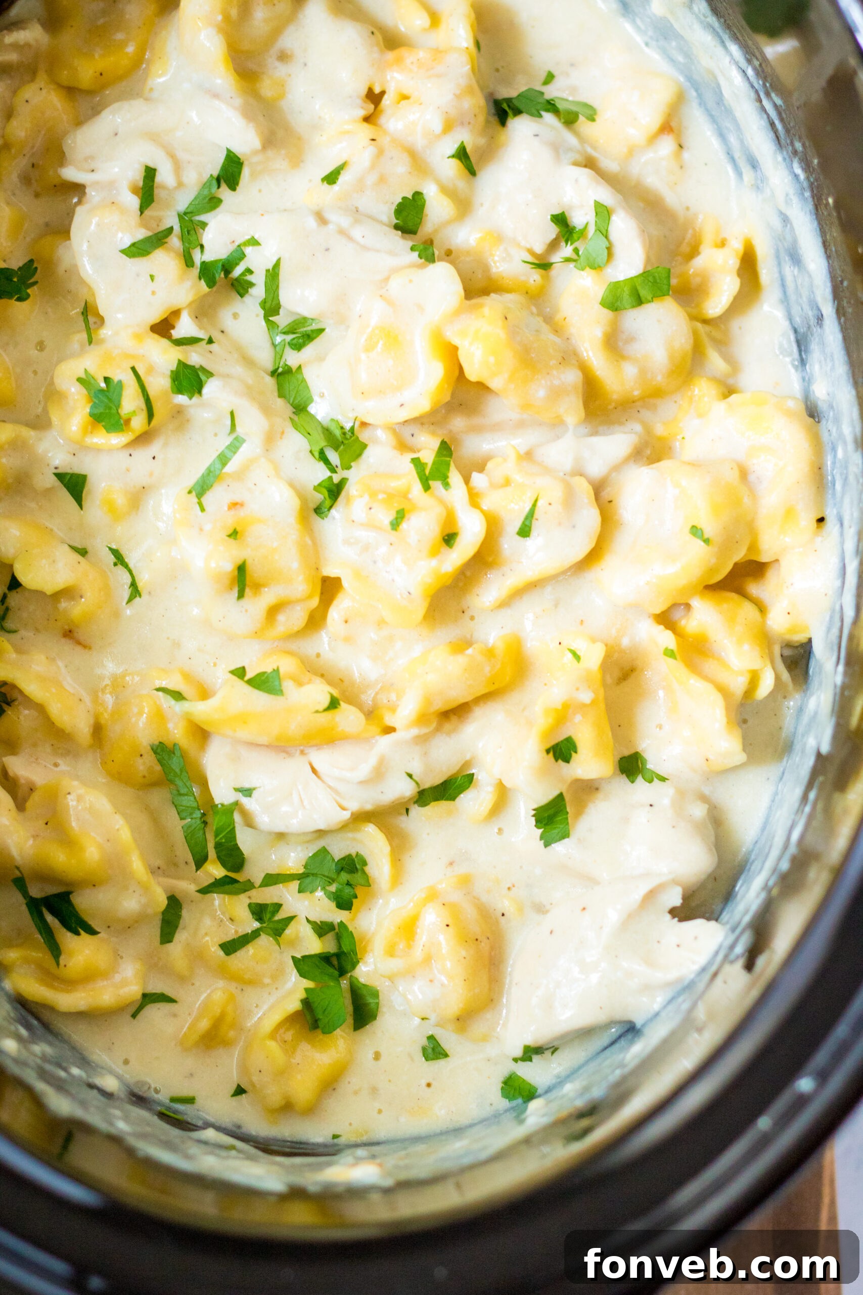 Close up view of creamy Slow Cooker Chicken Tortellini with visible tortellini and chicken pieces.