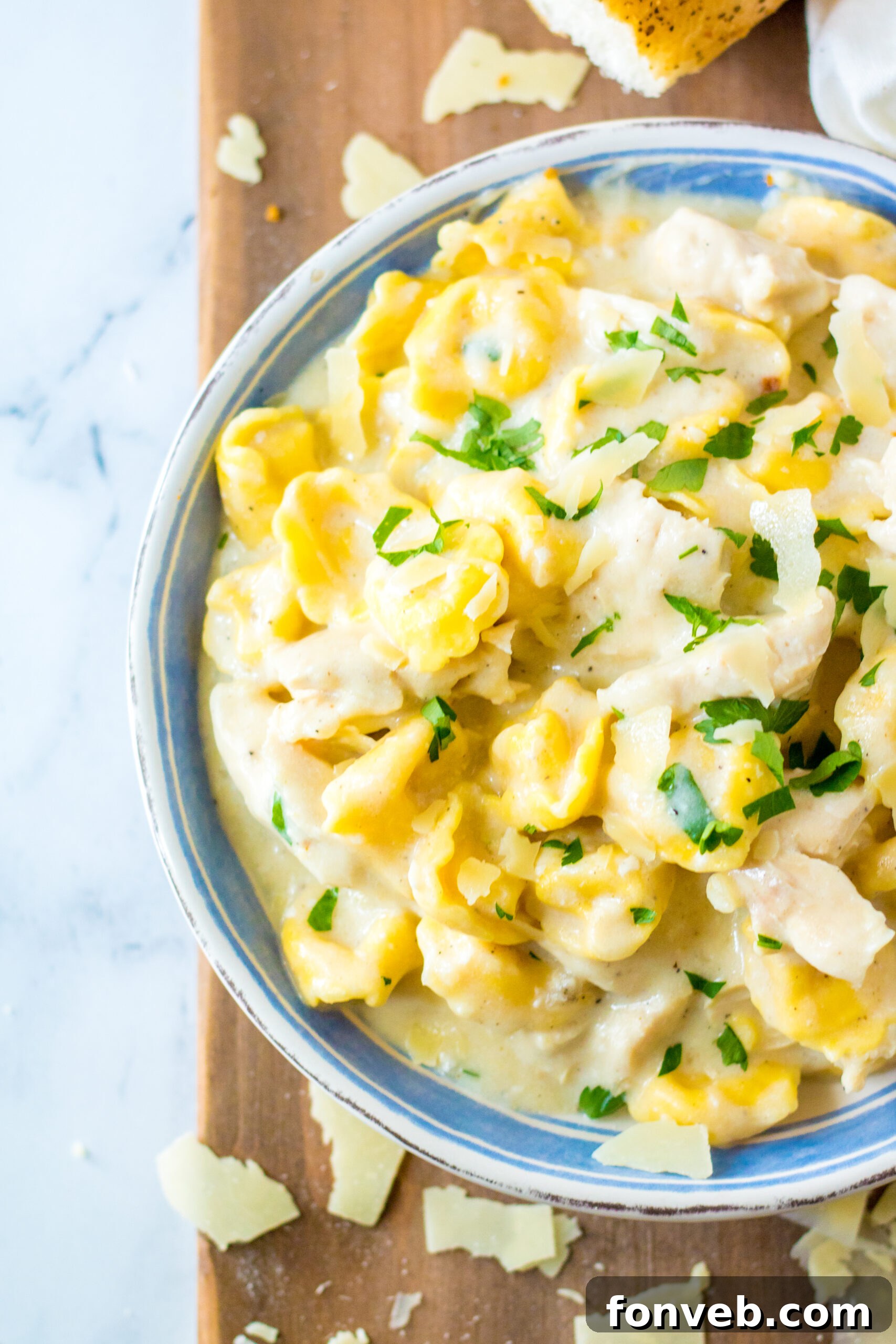 Close up view of Slow Cooker Chicken Tortellini in a white and blue bowl, showcasing the vegetables.