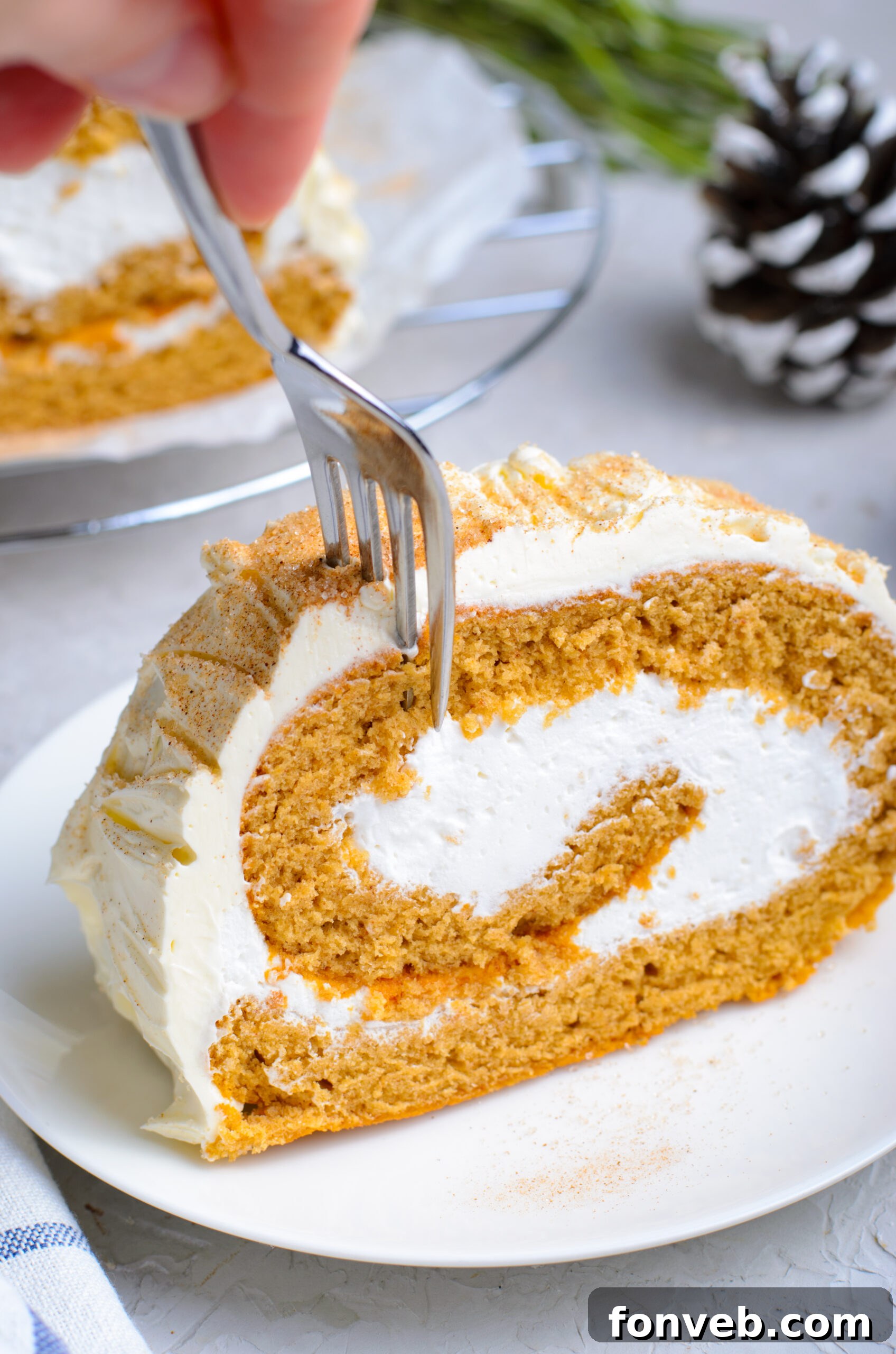 Front view of a silver fork removing a bite from a slice of GIngerbread Cake Roll.