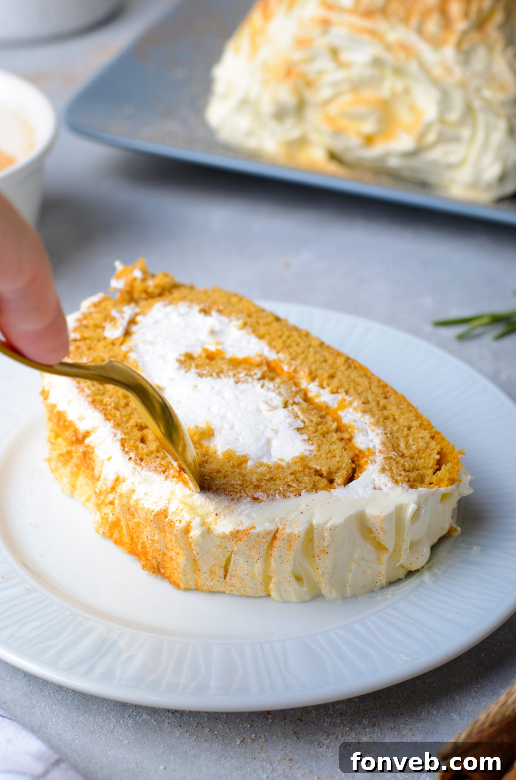 Close up view of a gold spoon removing a bite from a slice of GIngerbread Cake Roll.