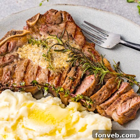 Overhead view of T Bone Steak on a white plate served with mashed potatoes.