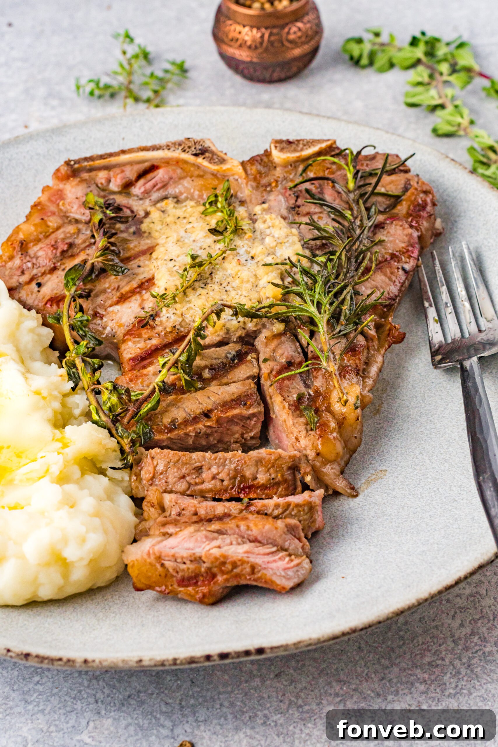 Front view of T Bone Steak on a white plate served with mashed potatoes.