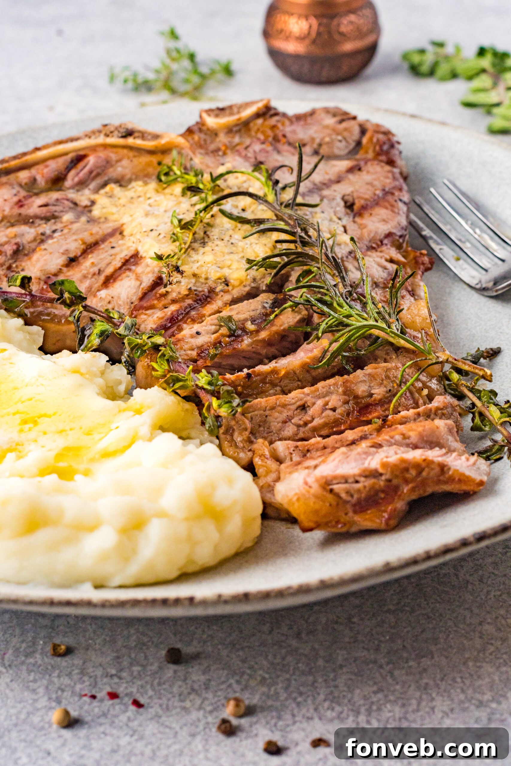 Front view of T Bone Steak on a white plate served with mashed potatoes.