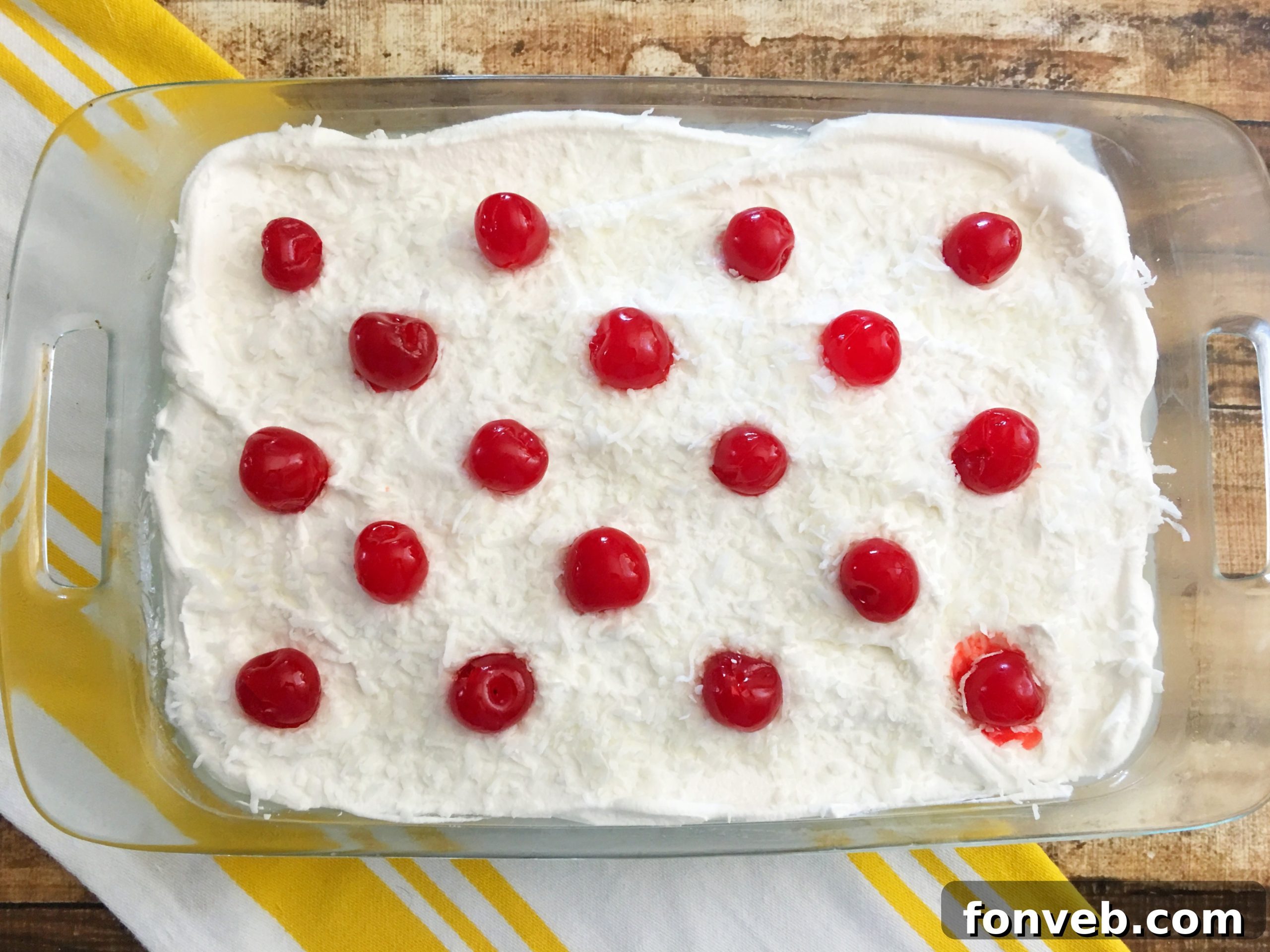 Whipped cream spread evenly over the chilled poke cake