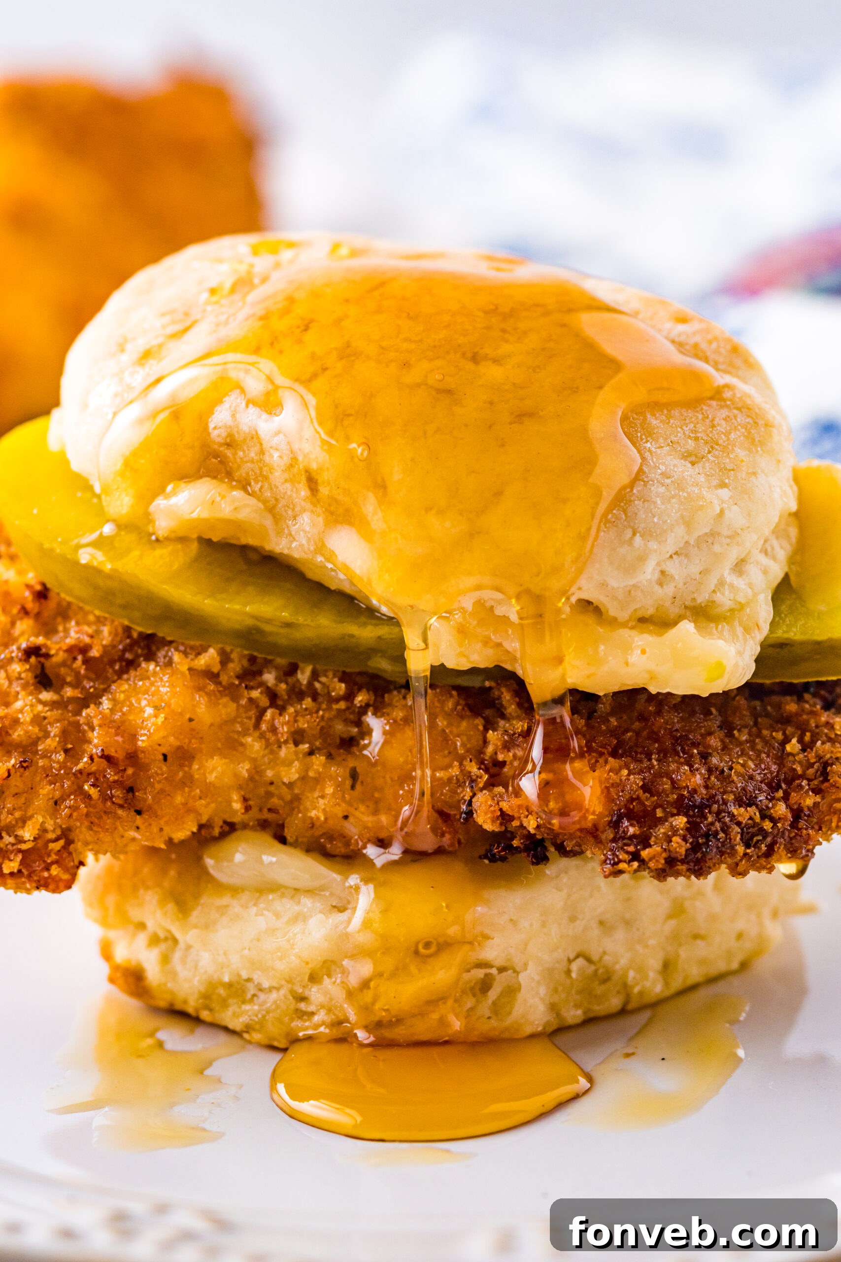 Front view of Honey Butter Chicken Biscuit on a white plate, showcasing its golden crust and fluffy biscuit.