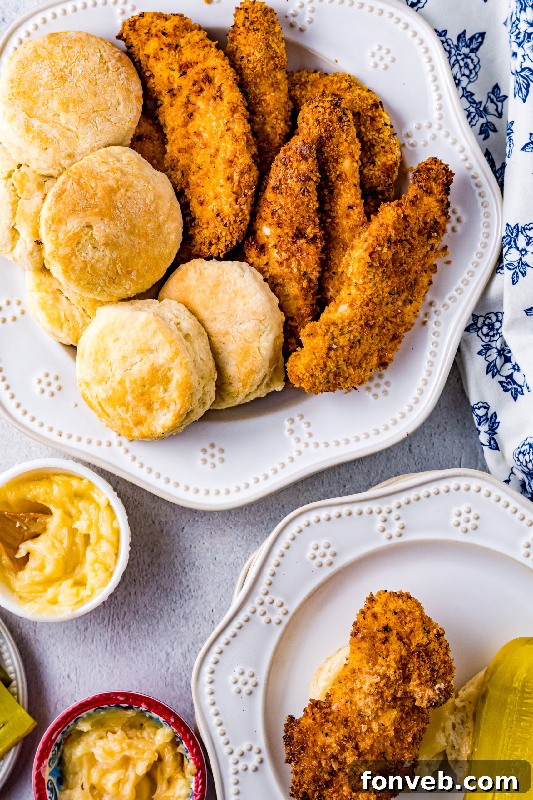 Overhead view of Honey Butter Chicken Biscuit unassembled on a white dish, showing the crispy chicken, soft biscuit, and dill pickles.