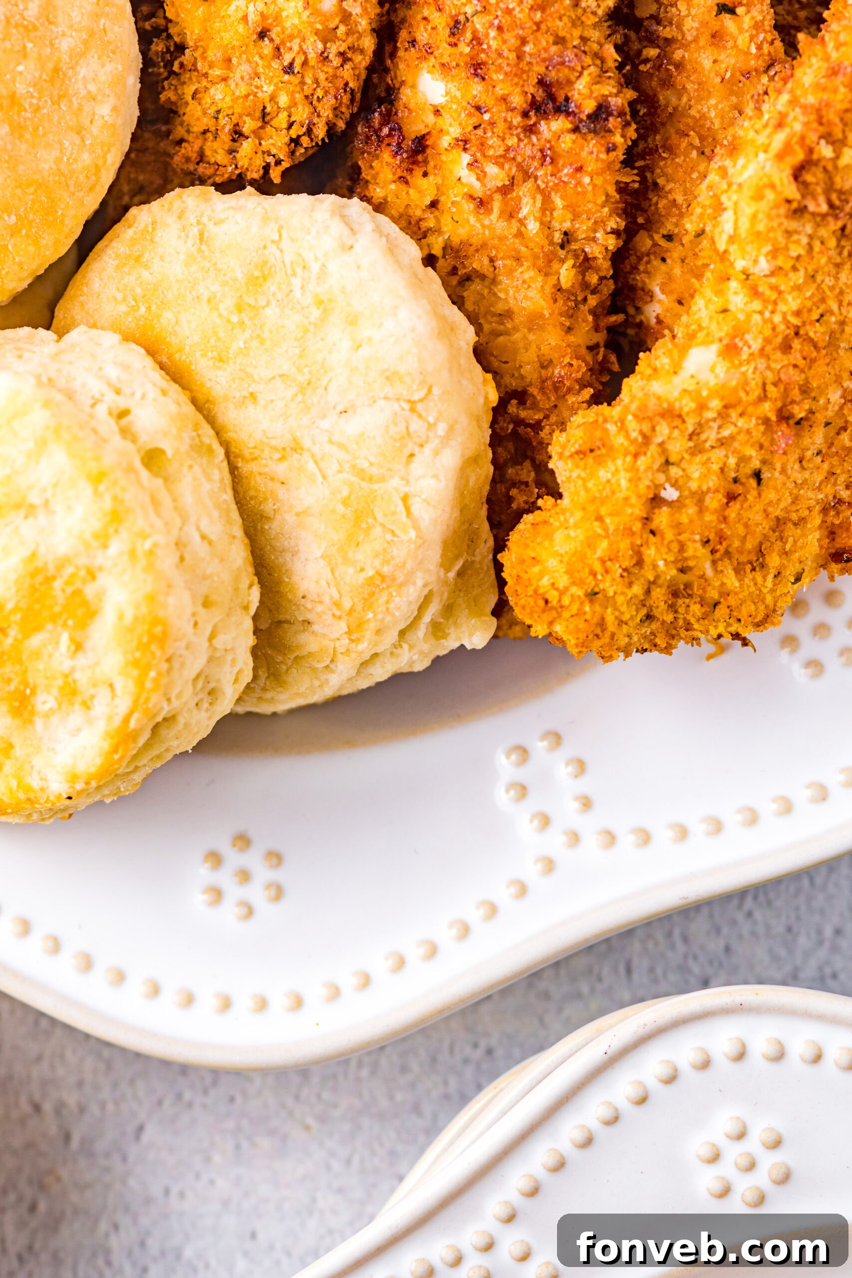 Close up view of Honey Butter Chicken Biscuit unassembled on a white dish, emphasizing the texture of the chicken breading.