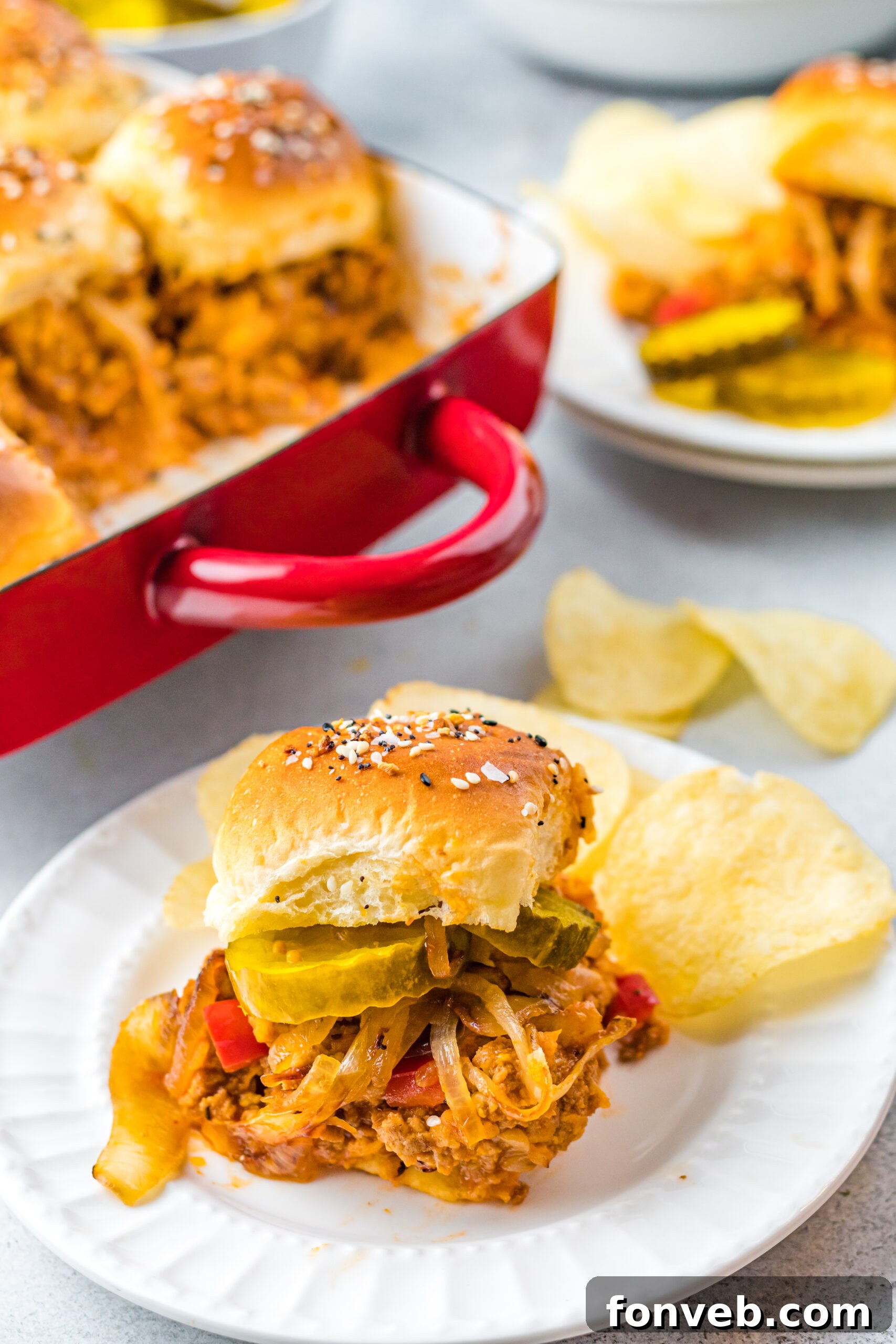 Front view of a Cheesy Chicken Sloppy Joe Slider on a white plate served with crispy chips, ready to eat.