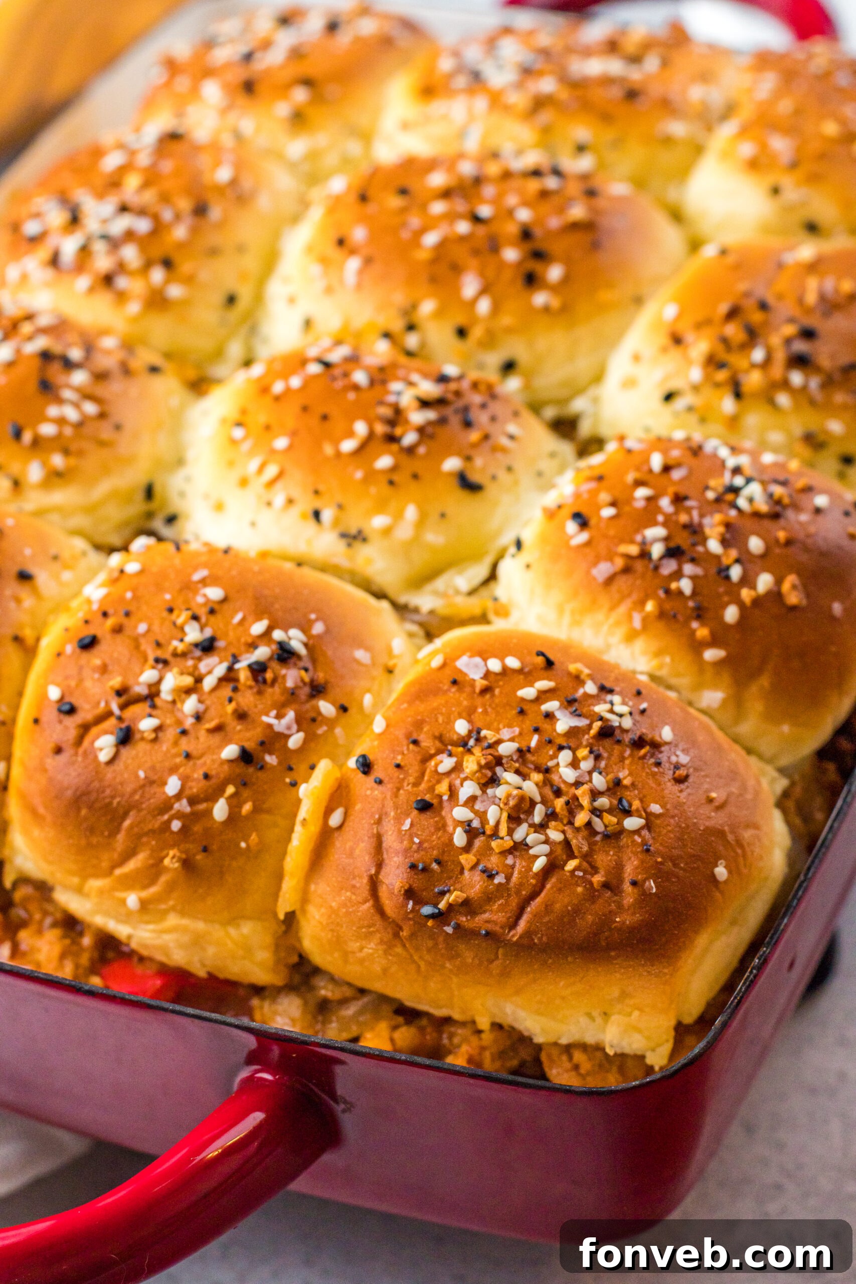 Overhead view of Cheesy Chicken Sloppy Joe Sliders in a vibrant red baking dish, garnished and ready.
