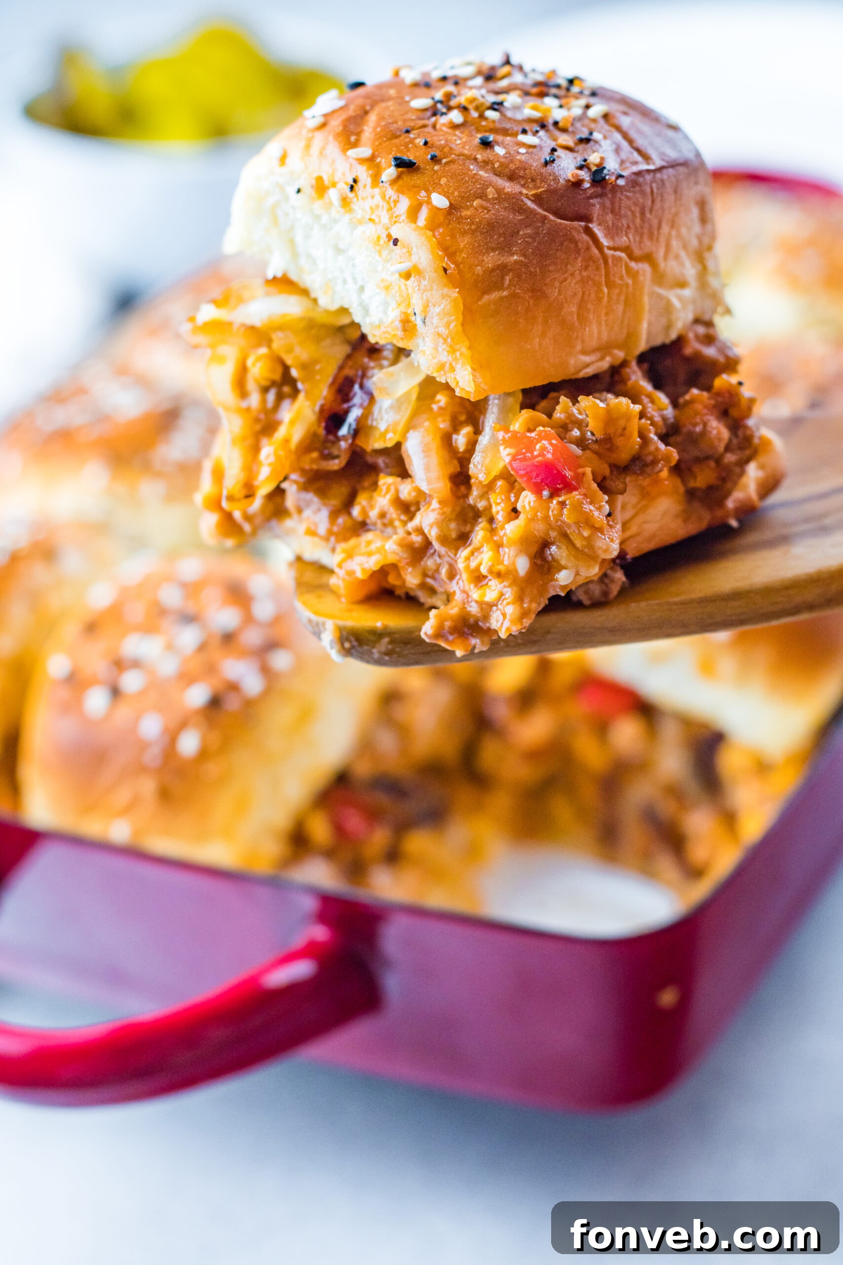 Front view of a single Cheesy Chicken Sloppy Joe Slider on a wooden spatula, showcasing its cheesy filling.