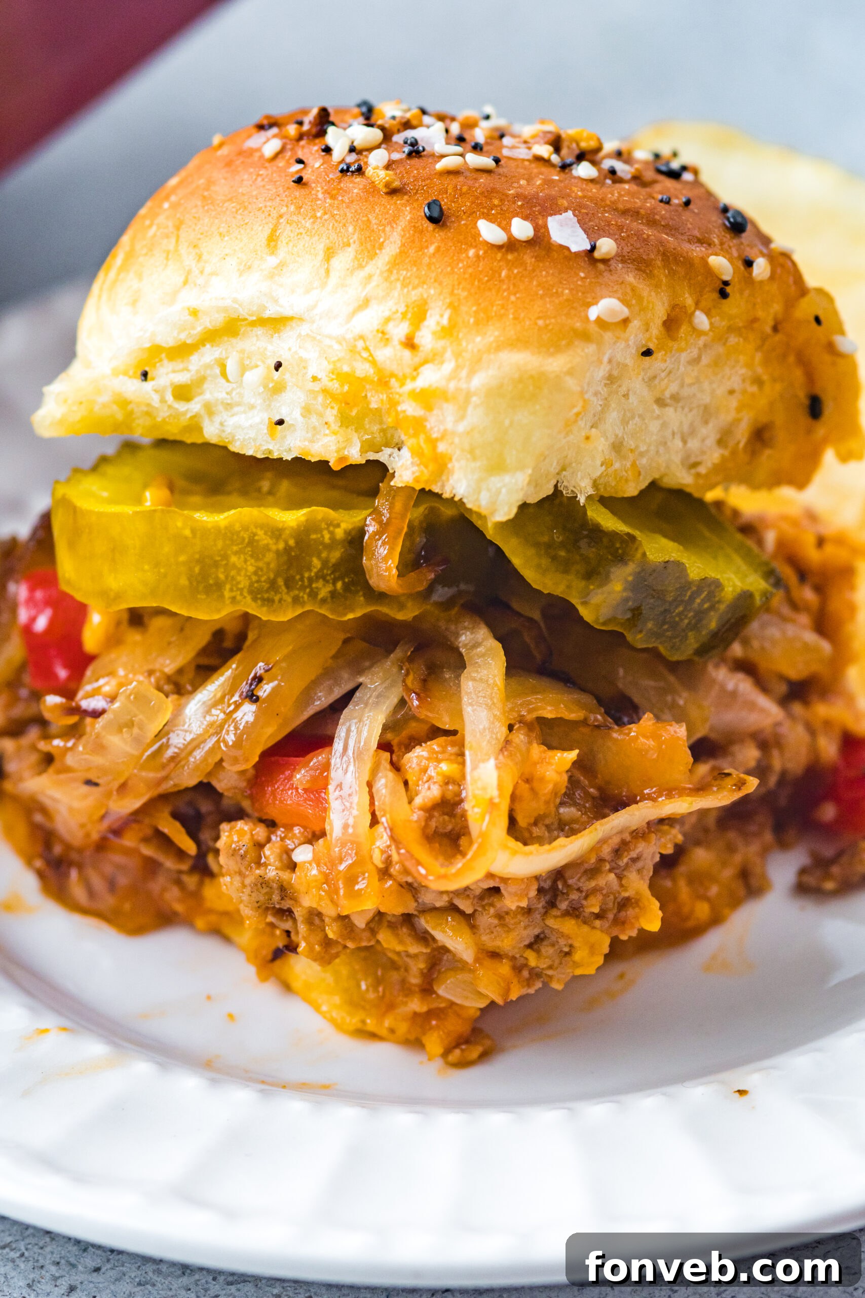 Front view of a Cheesy Chicken Sloppy Joe Slider on a white plate, showcasing its golden-brown bun and rich filling.