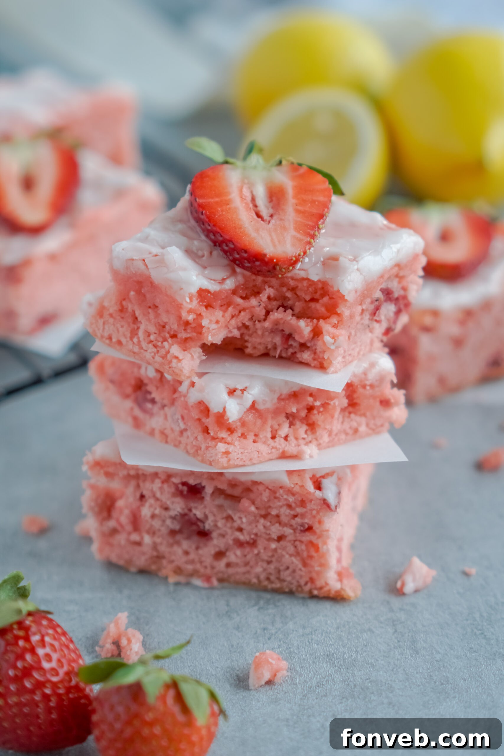 Stacked Strawberry Lemon Brownies with a bite taken from the top one, showcasing the soft, moist interior and pink hue.