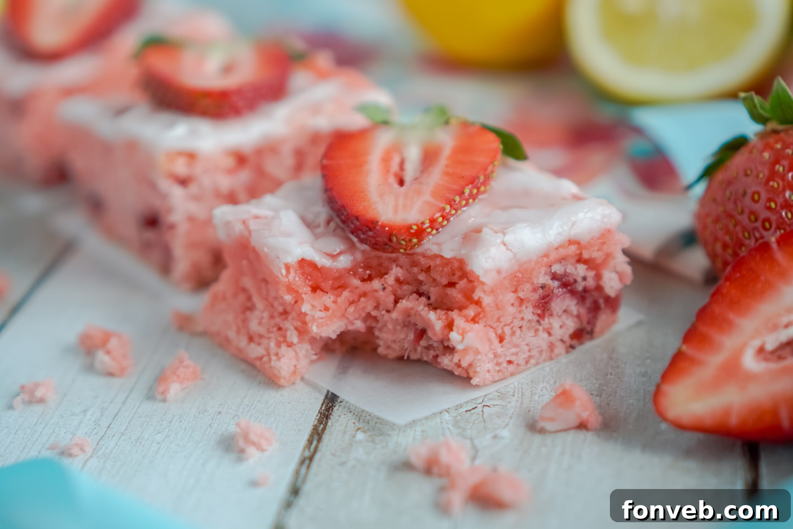 Side profile of a Strawberry Lemon Brownie with a bite removed, showing its soft interior and the delicate glaze.