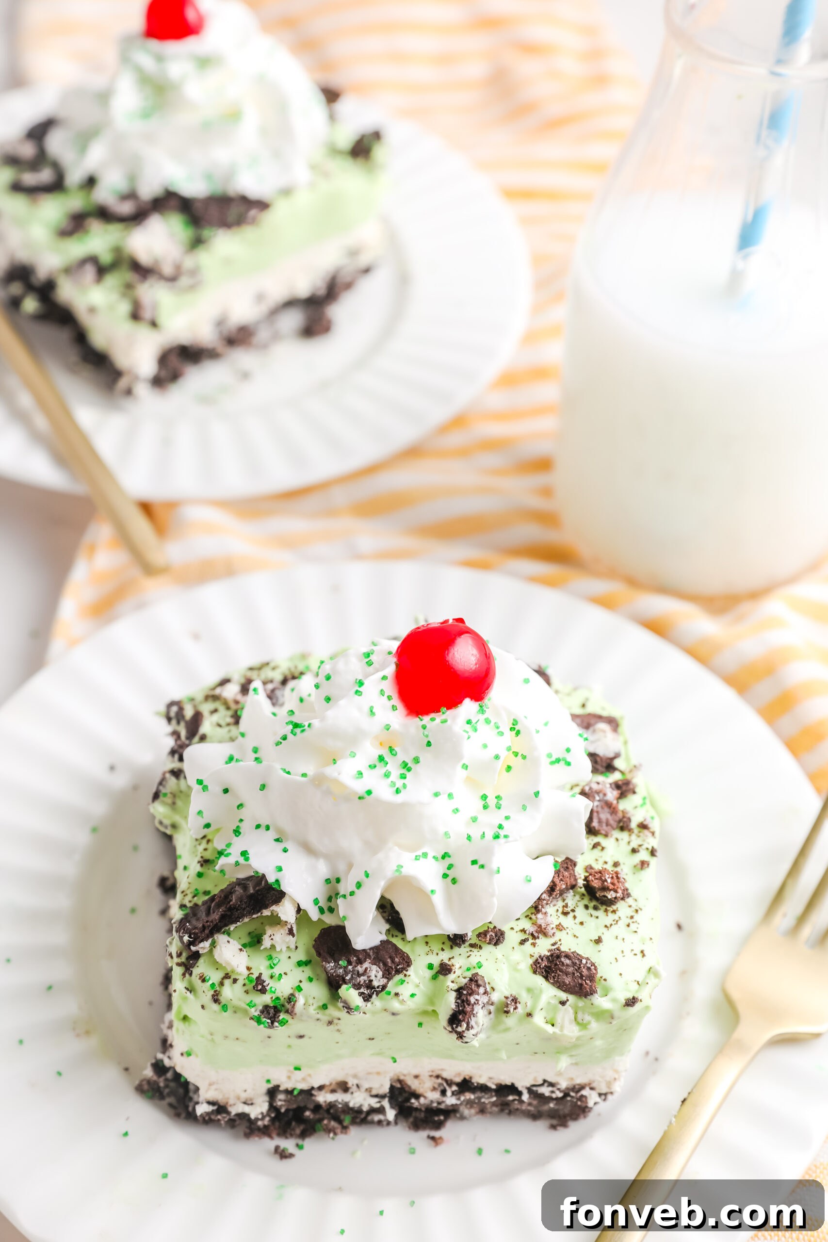 Emerald Lasagna 11 Two individual servings of Shamrock Lasagna dessert on white plates, each with a gold fork, emphasizing their perfect presentation.