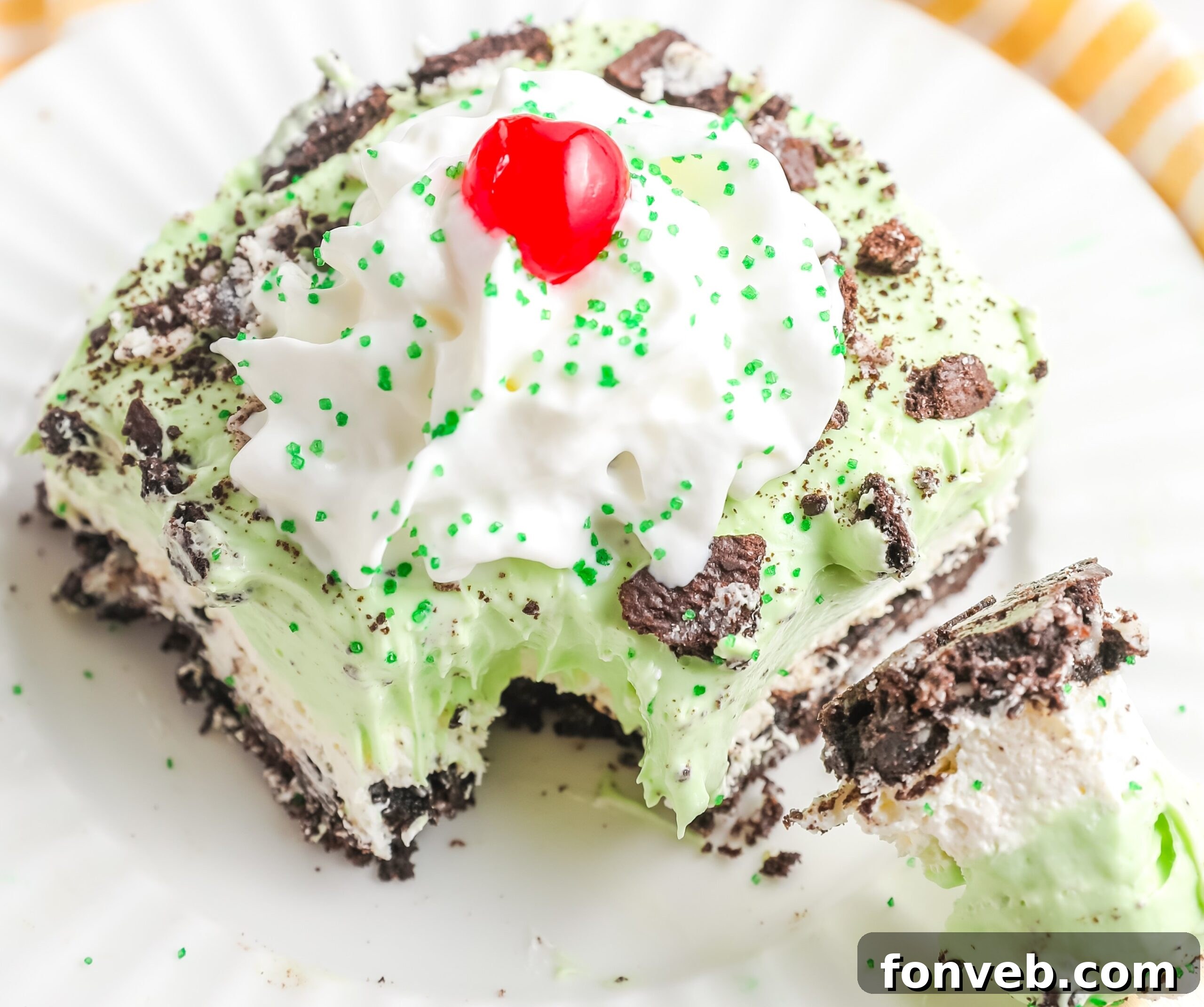 Emerald Lasagna 6 A close-up side angle of a slice of Shamrock Lasagna on a white plate, with a bite taken out by a fork, showcasing the multiple layers.