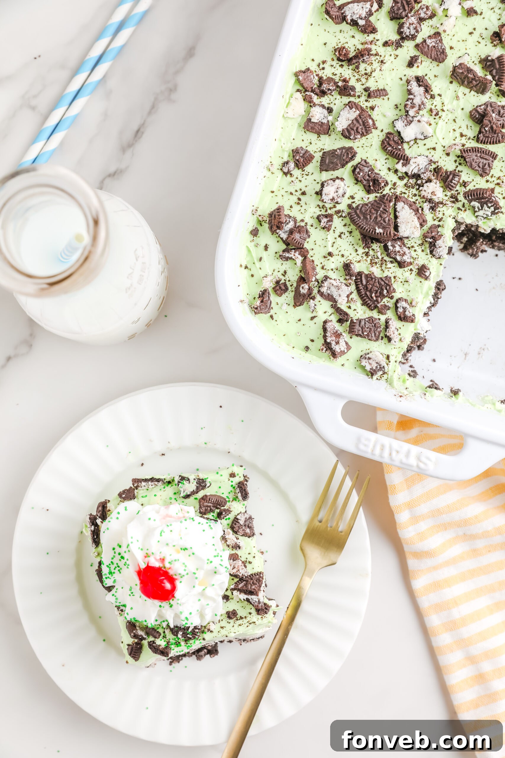 Emerald Lasagna 8 An overhead shot of the Shamrock Lasagna in a baking dish, with a slice removed and placed on a white plate with a gold fork, ready for serving.