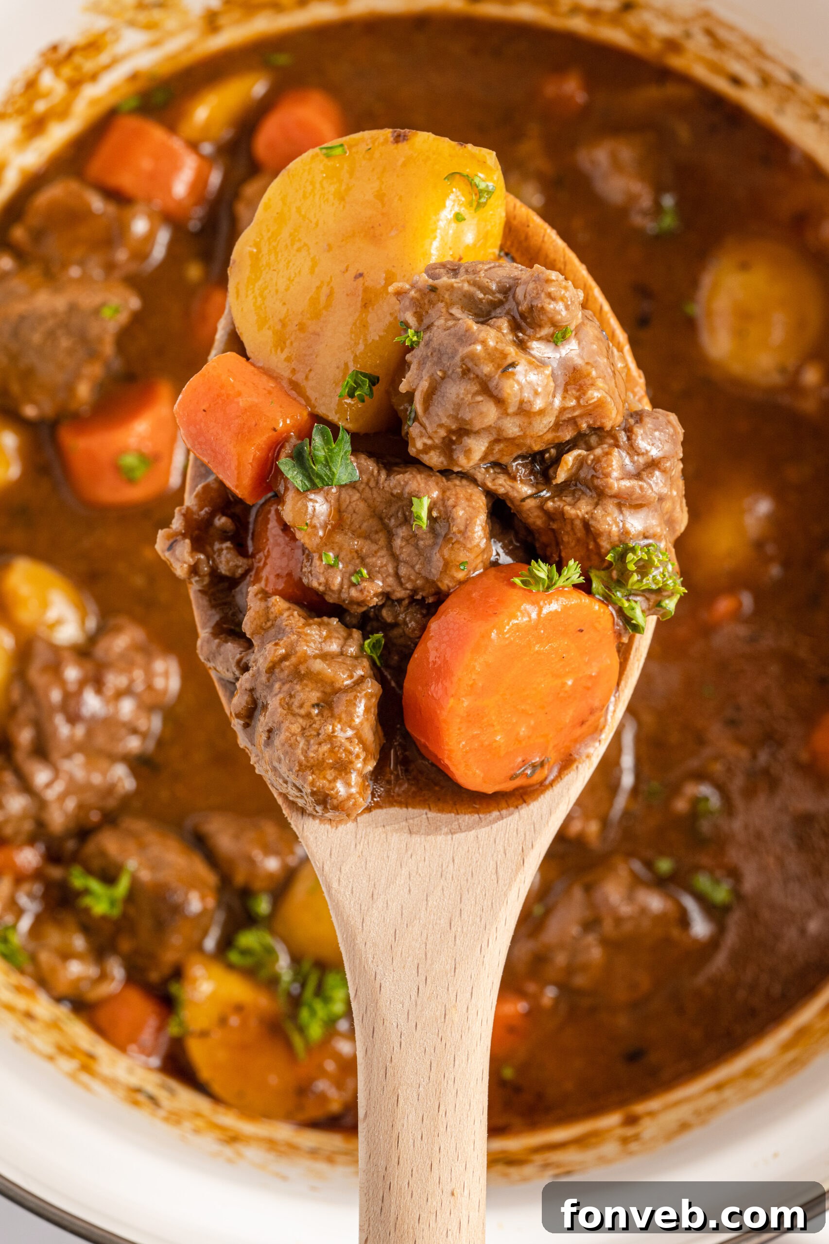 A wooden spoon holding Irish Stew over a large cooking pot. 