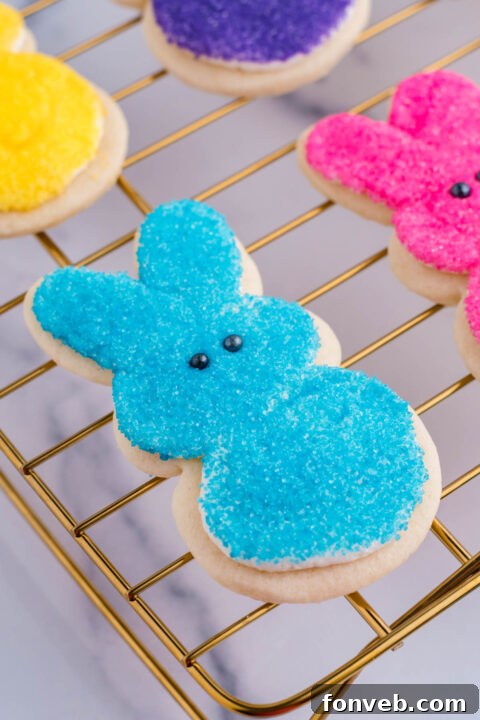 A blue bunny cookie being adorned with black sugar pearls for eyes, bringing its cheerful face to life.