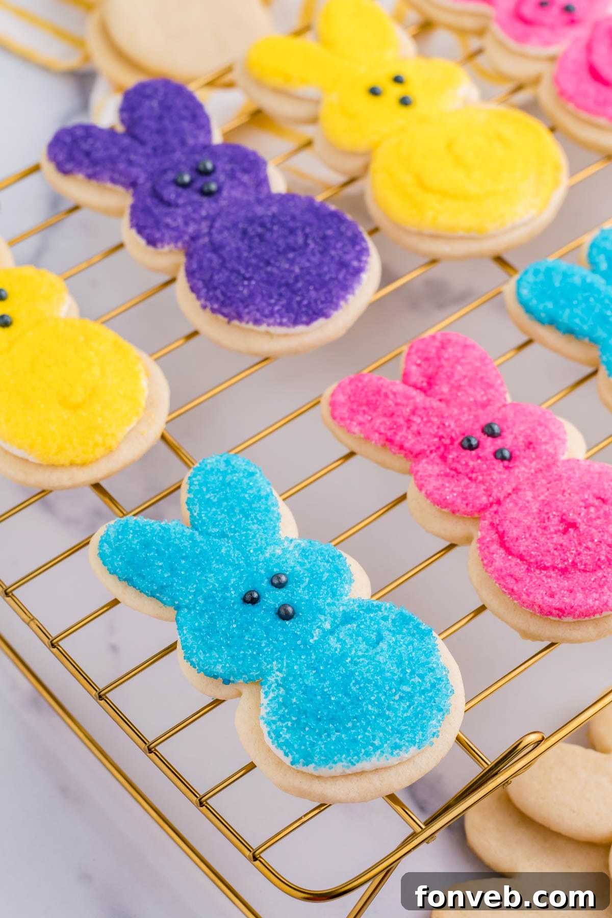 A delightful side view of multicolored Easter Bunny Cookies, artfully arranged on a gold cooling rack, showcasing their cheerful colors and tempting frostings.