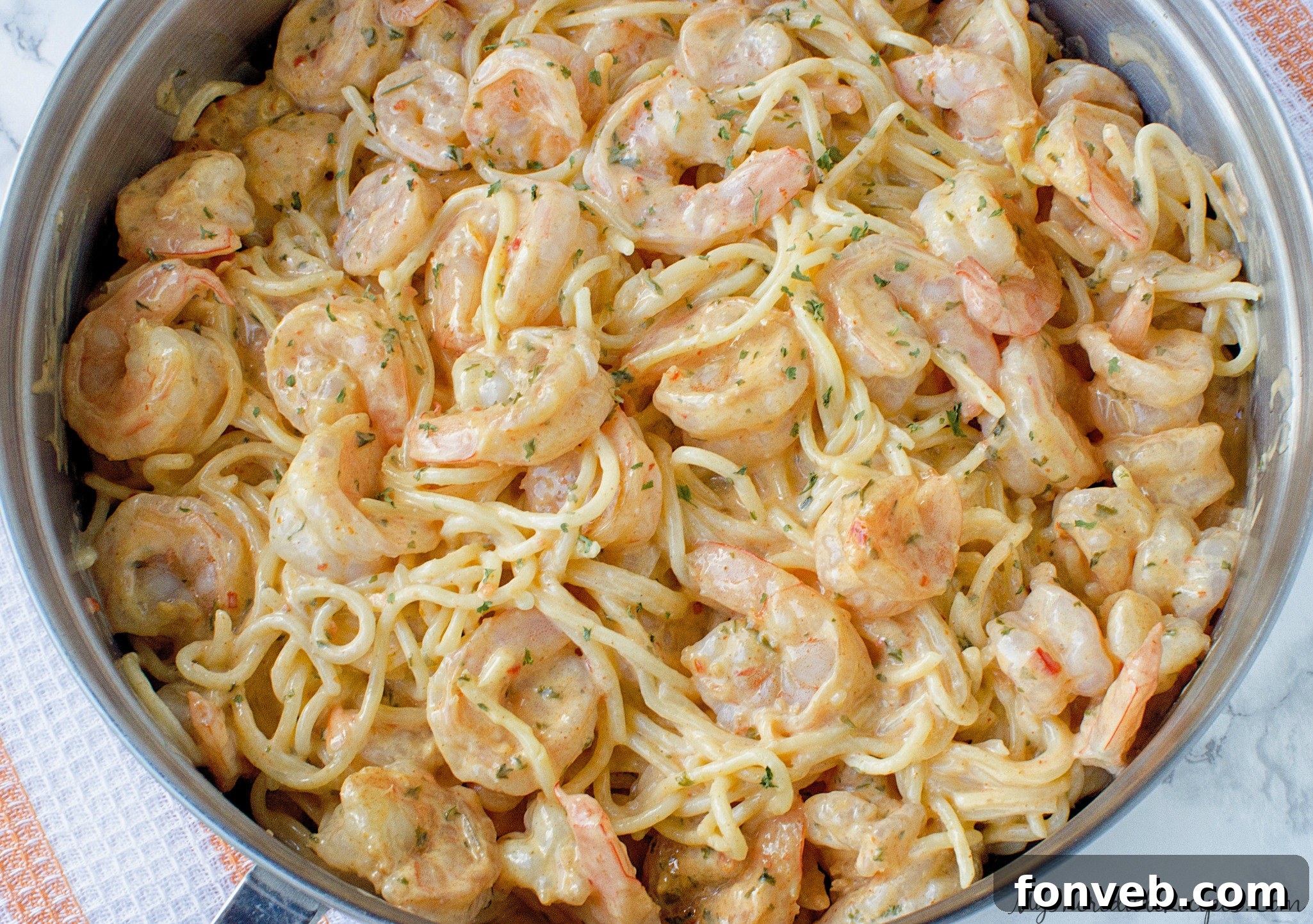 Shrimp cooking in a hot skillet with seasonings.
