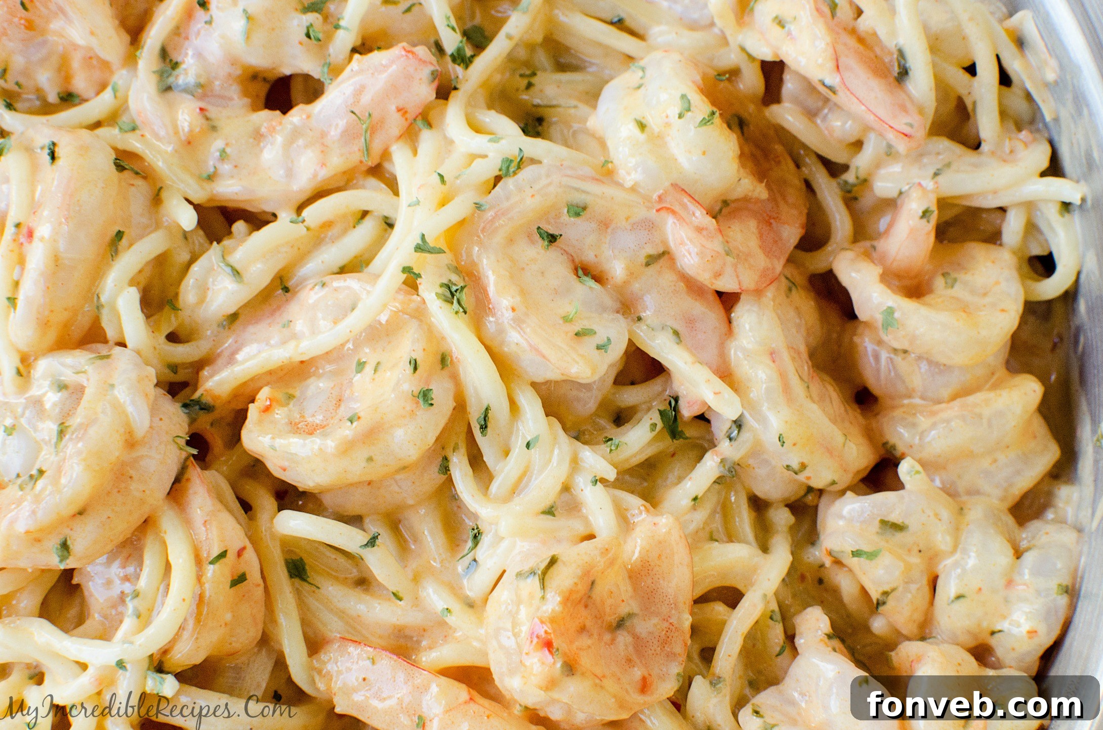 Cooked shrimp and pasta being tossed together in a large bowl.
