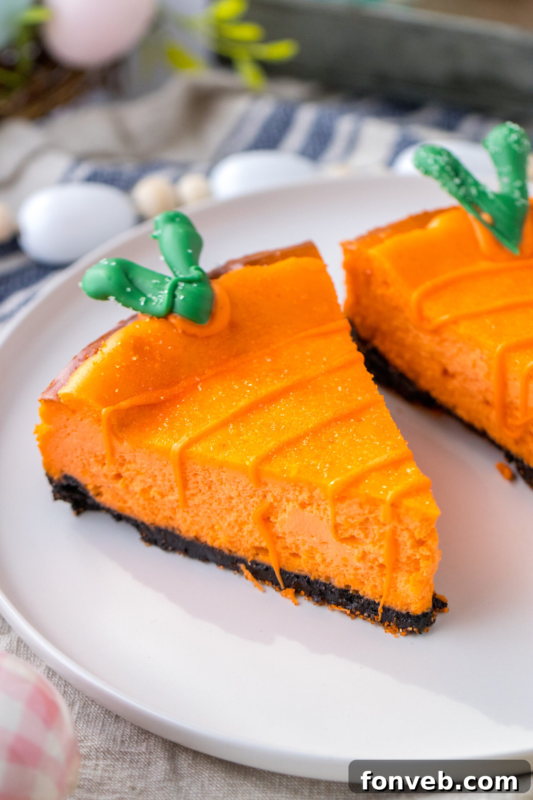 Two vibrant, carrot-shaped cheesecakes, adorned with green candy melt stems, rest on a pristine white plate, ready for an Easter celebration.