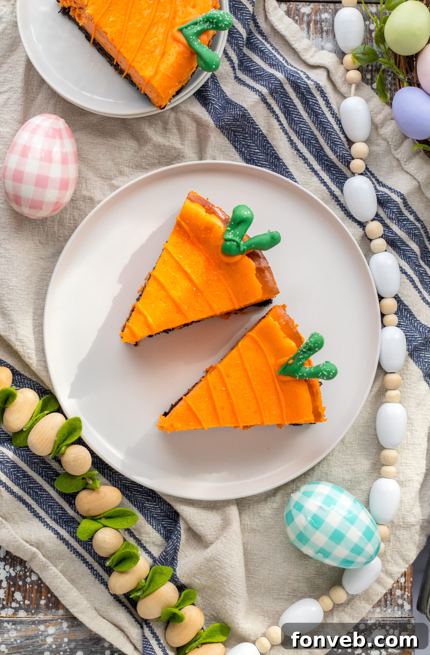 Three perfectly crafted cheesecake carrots are presented on two white plates, with a charming blue and white linen gently folded in the background.