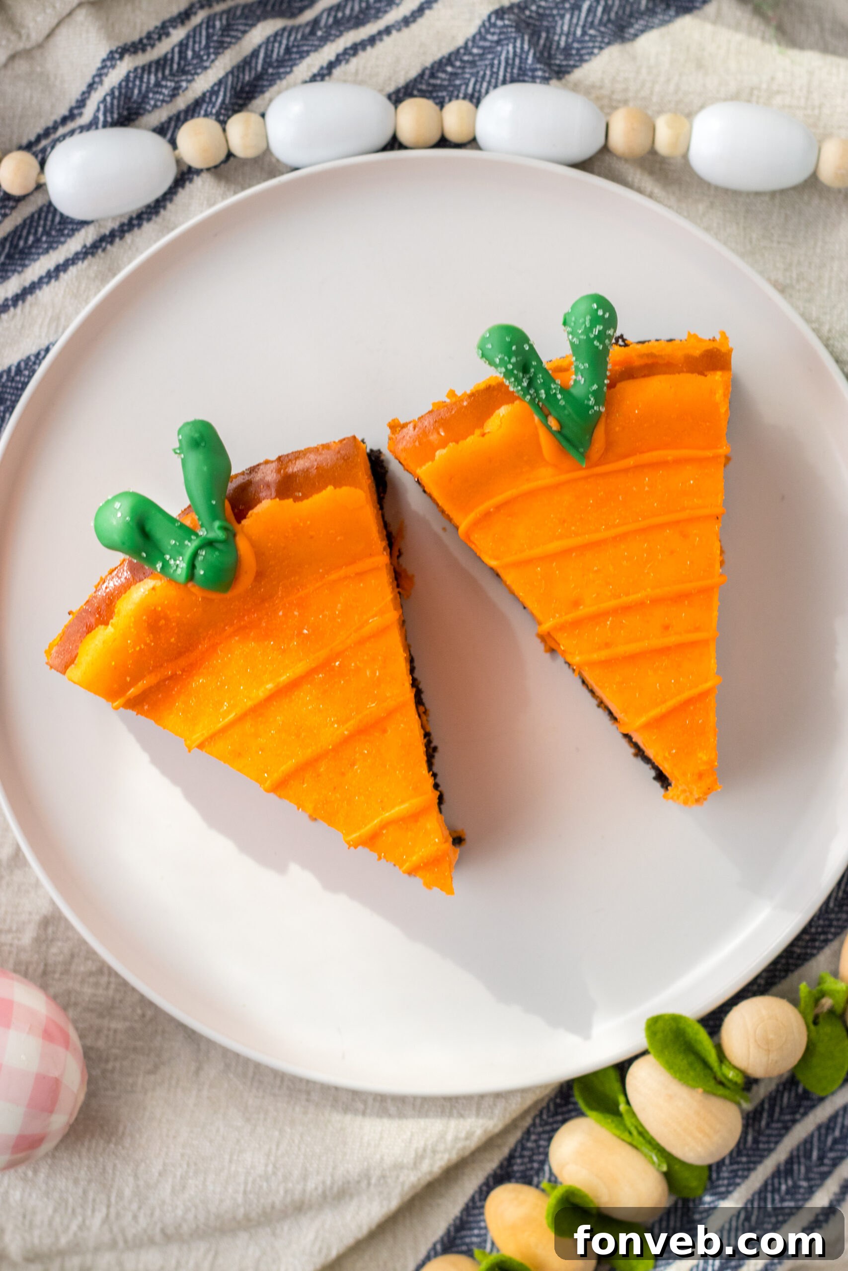 An overhead perspective showcasing two exquisite cheesecake carrots, presented beautifully on a clean white plate.