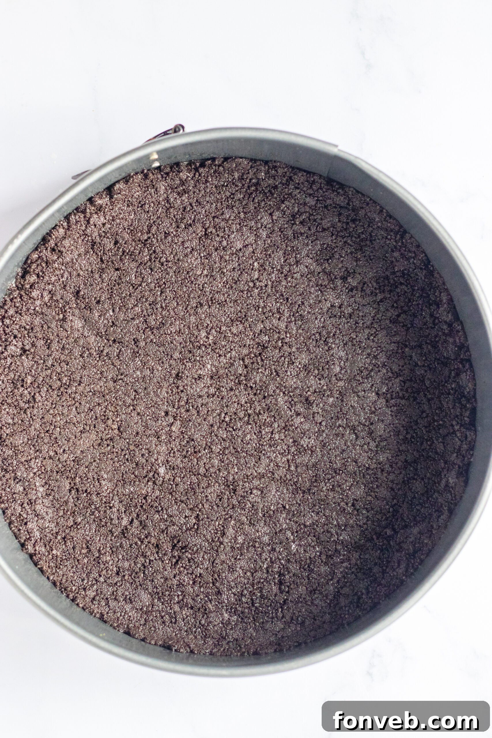 A bowl of crushed Oreo crumbs, ready to be mixed for the cheesecake crust.