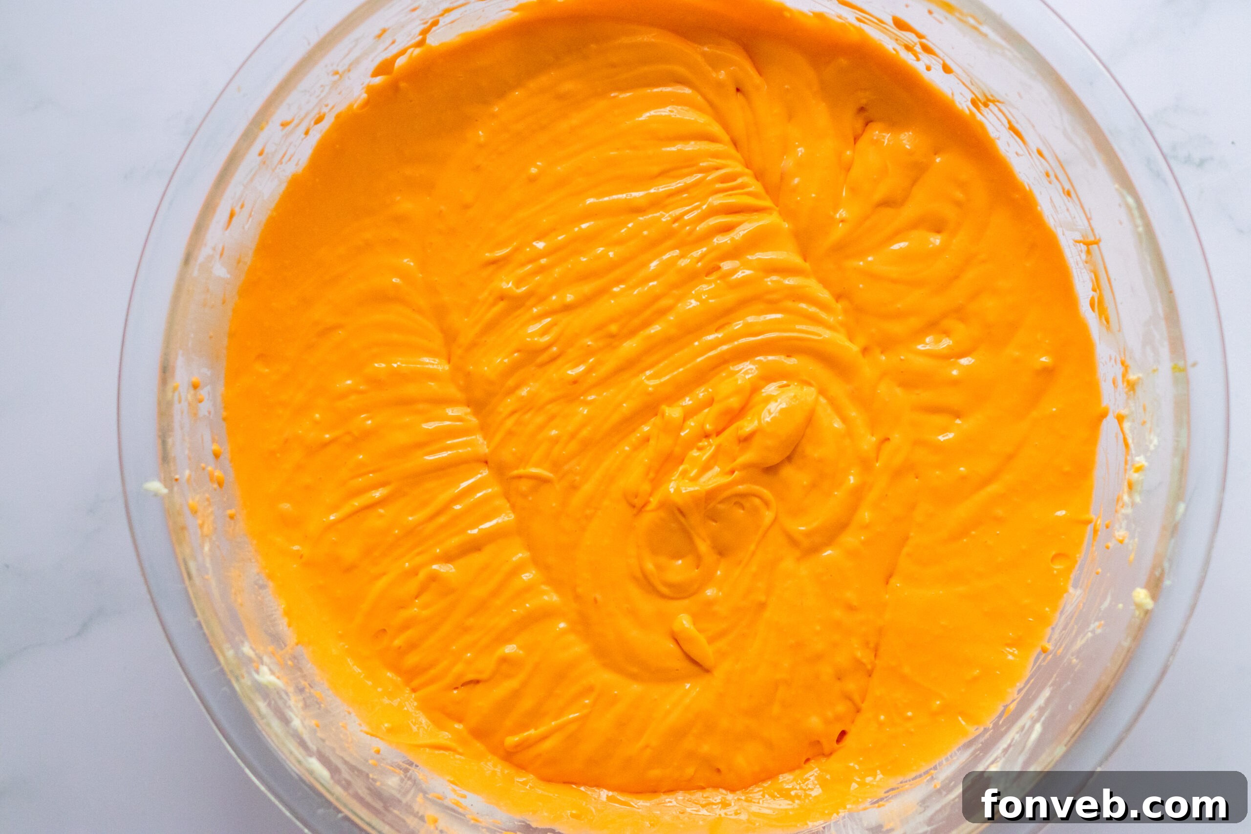 Melted butter being poured into a bowl of Oreo crumbs, a crucial step for the crust.