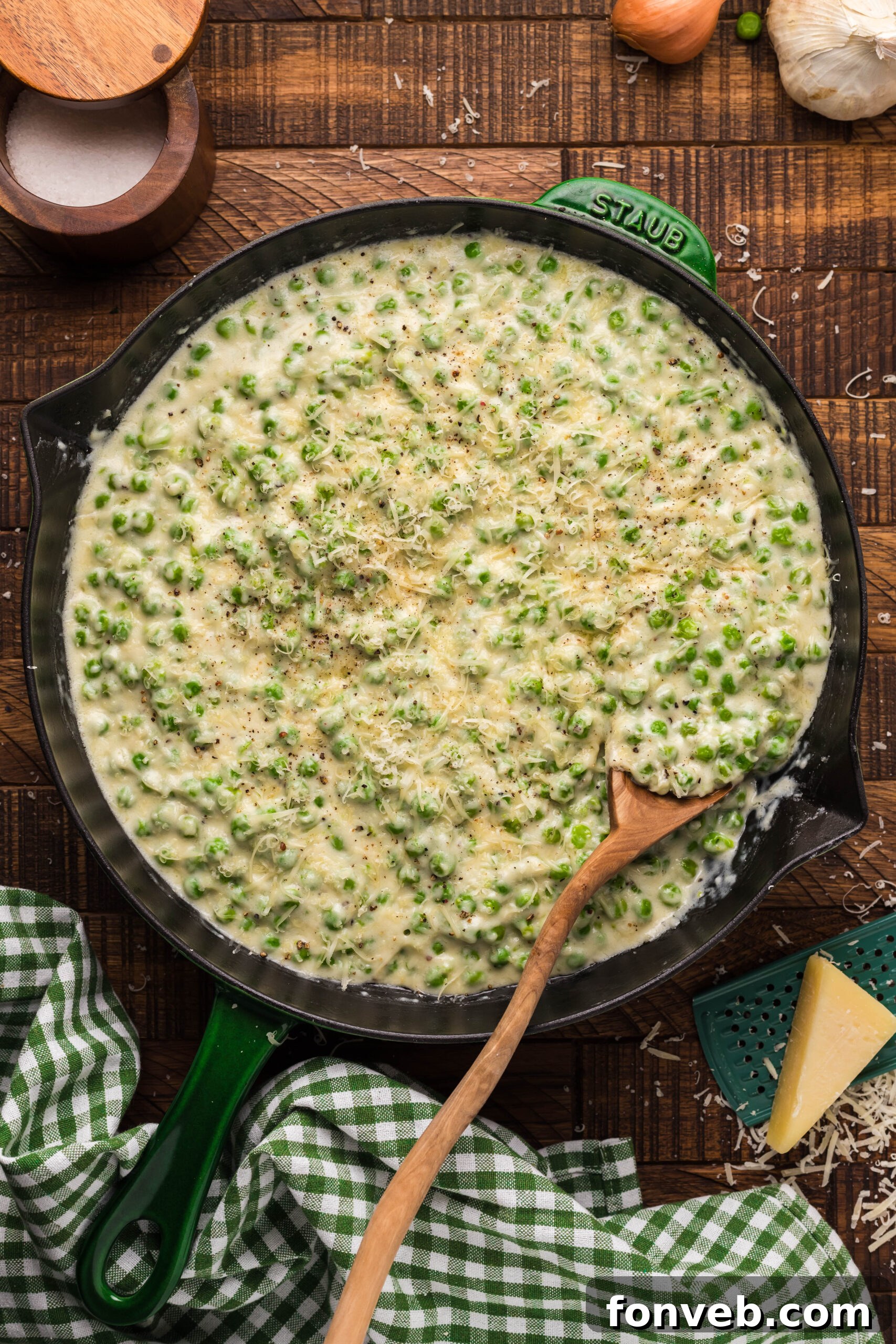 Creamed Peas in a black and green cast iron skillet with a wood spoon. 
