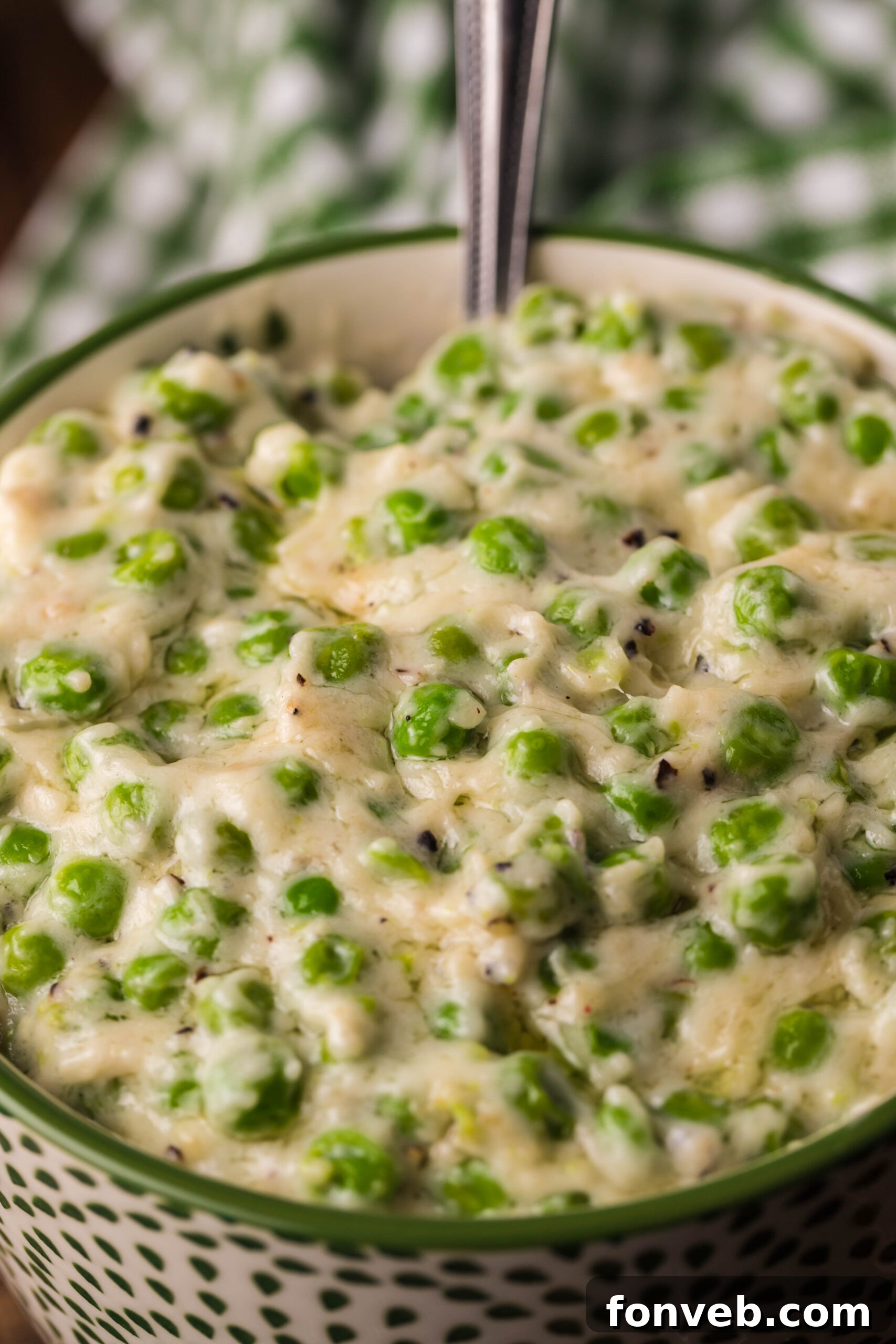 Close up shot of creamed peas in a green and white bowl. 