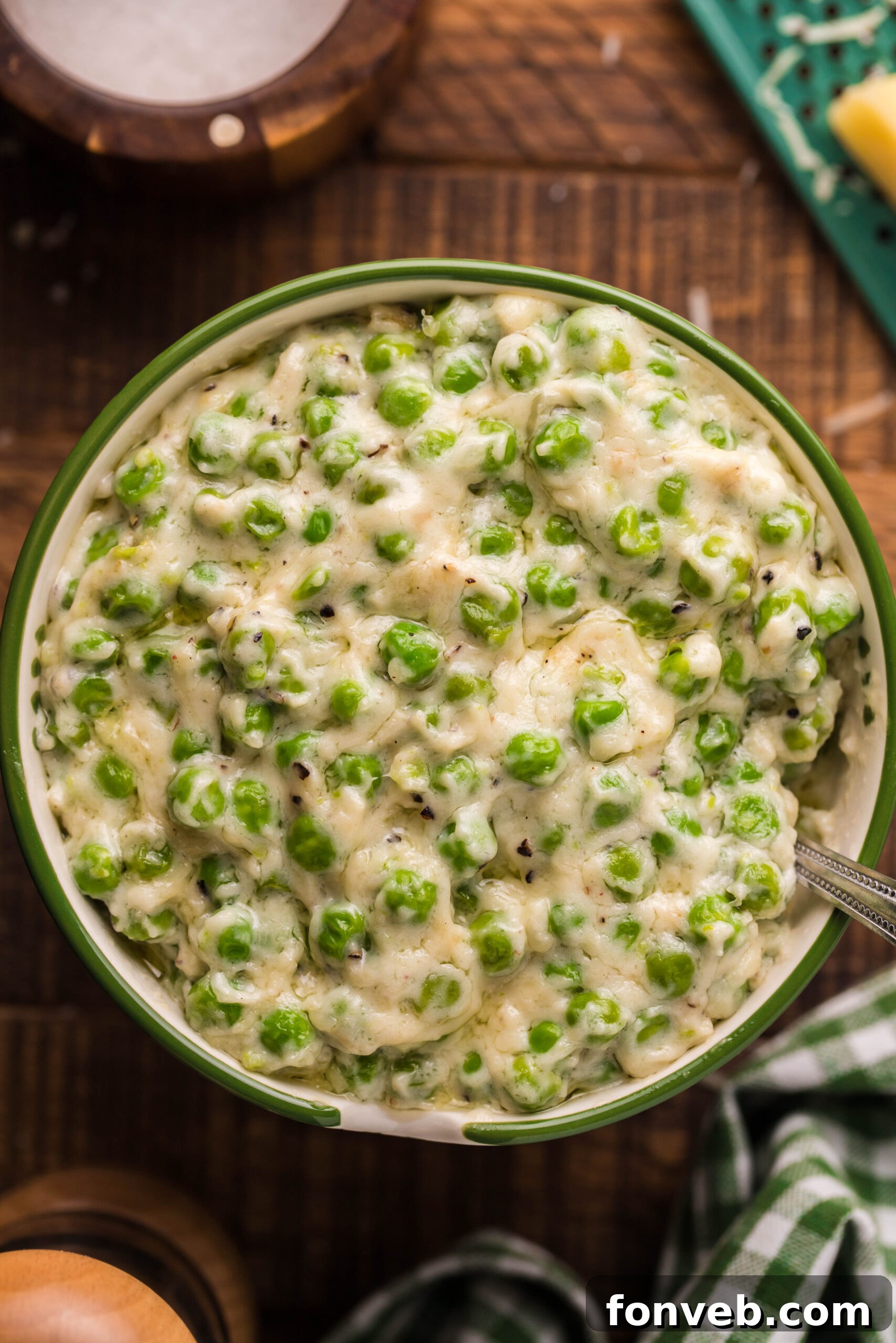 Close up shot of creamed peas in a green and white bowl. 