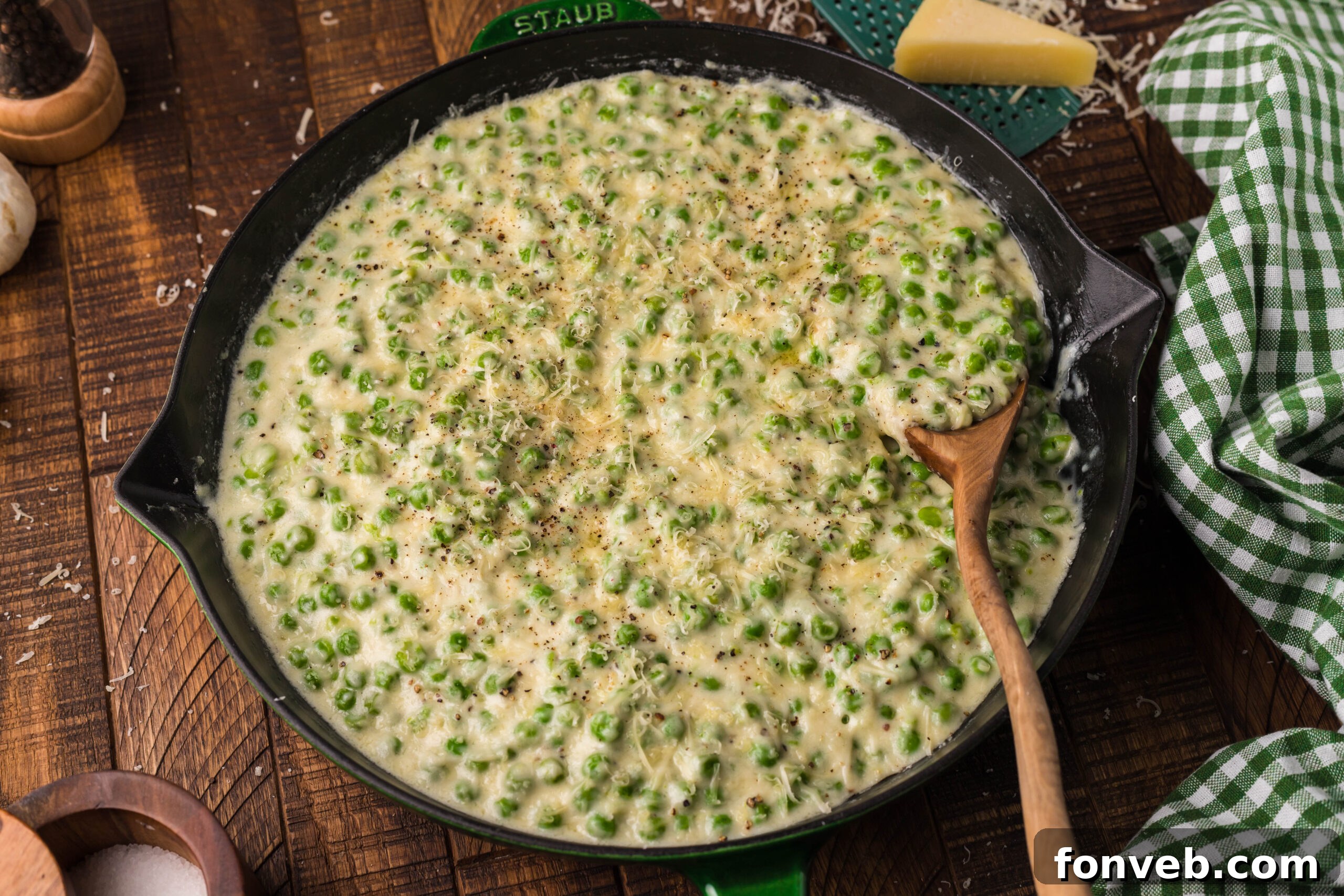 Creamed Peas in a black and green cast iron skillet with a wood spoon. 