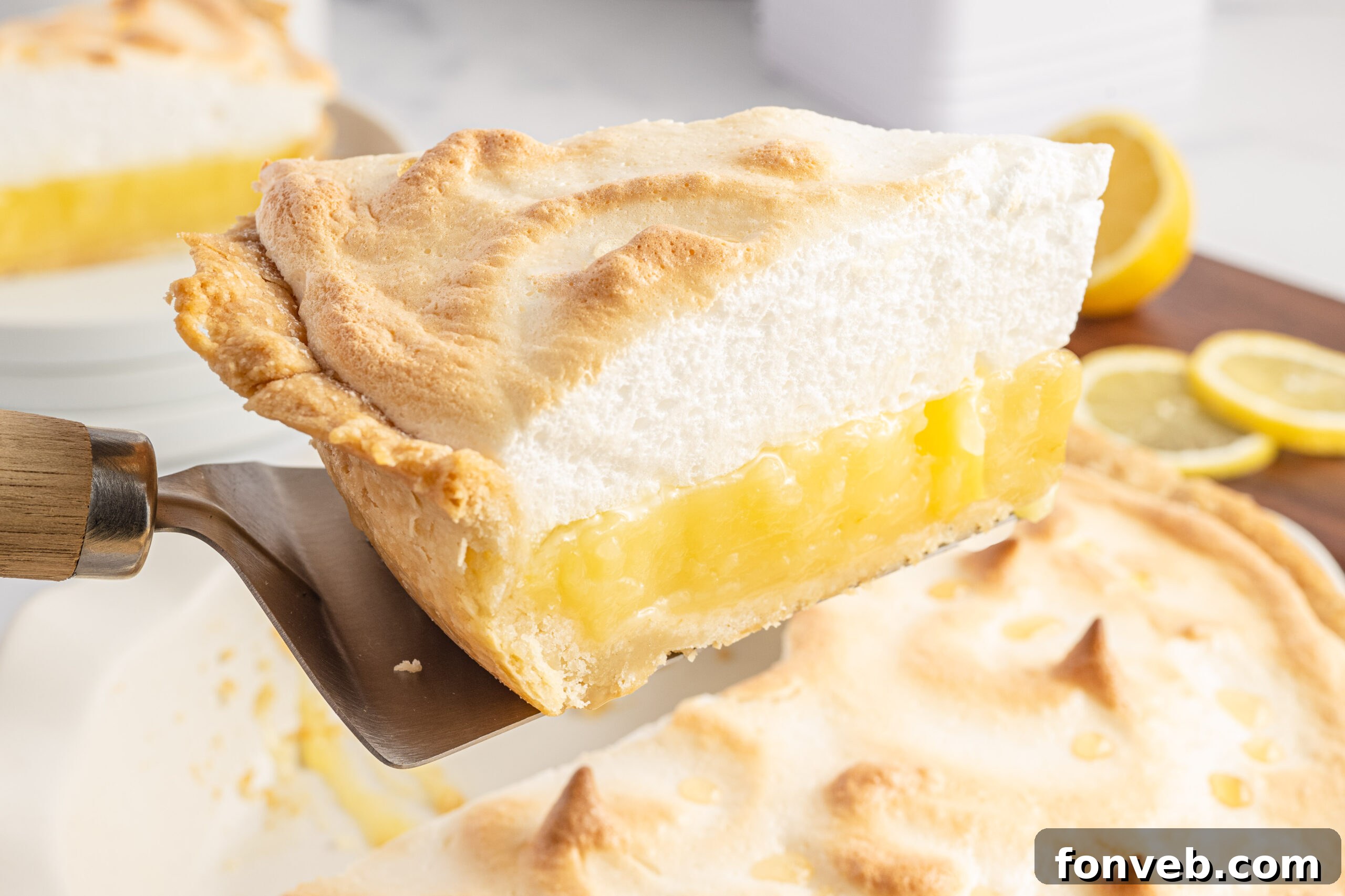 A slice of lemon pie being held up by a silver and wooden spatula. 