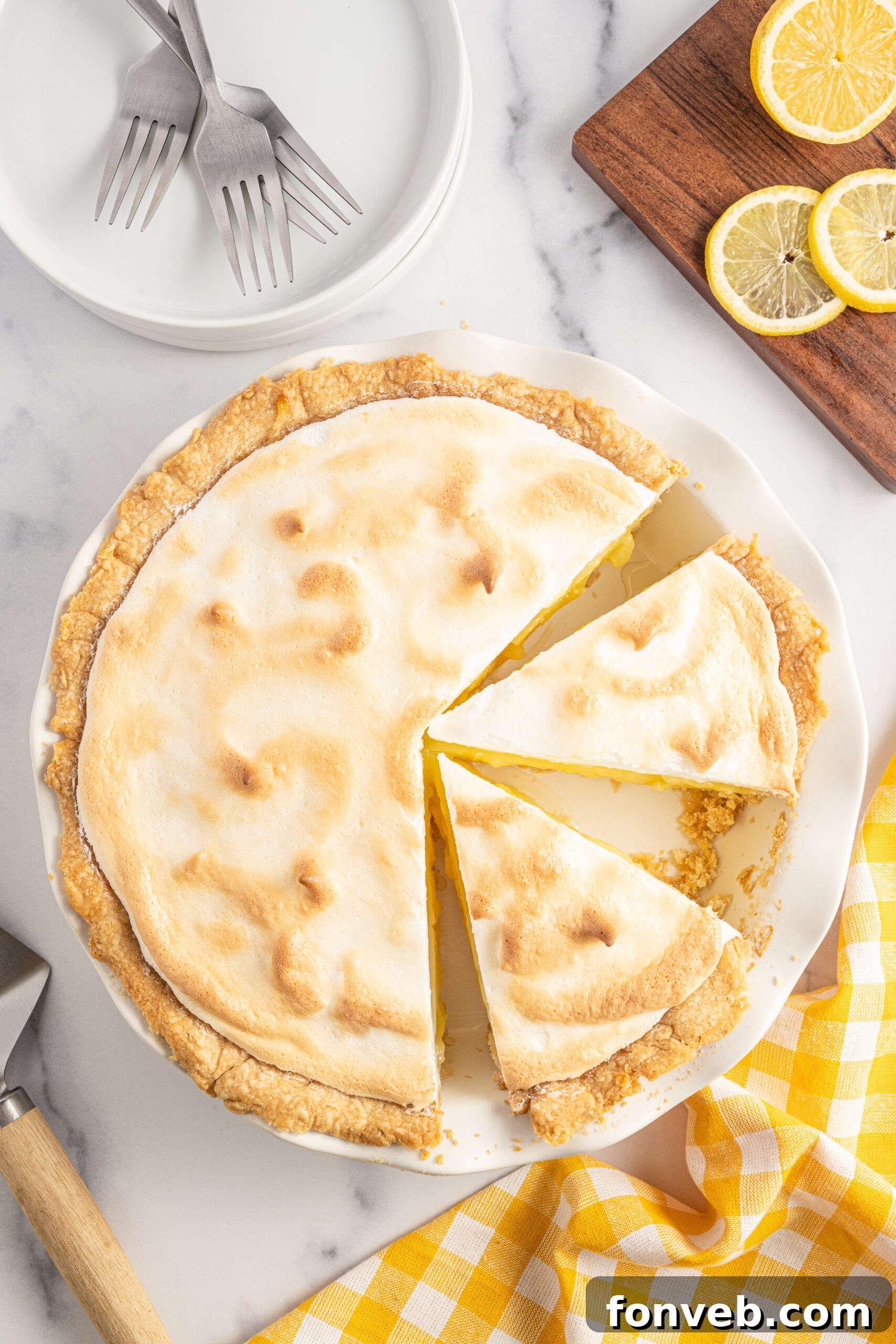 Overhead shot of two slices of lemon meringue pie in a white pie dish. 