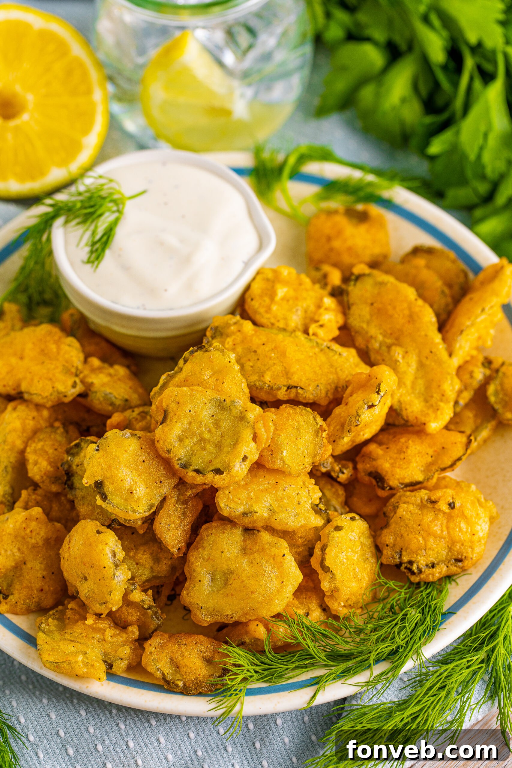 Overhead view of Fried Pickles on a white plate with ranch and fresh dill in the background. 